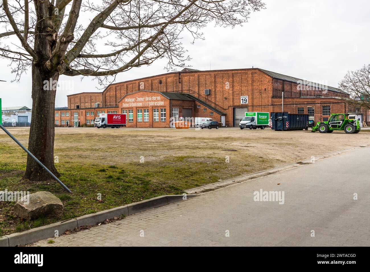 Ehemalige Industriebauten dienen als Produktionsstätten für Studio Babelsberg. Einschließlich des weltweit größten grünen Außenbereichs. Potsdam, Brandenburg, Brandenburg, Deutschland. Noch heute steht der Slogan aus der DDR-Zeit über dem Eingangsbereich: 'Kollege, immer vergessen: Ihre Arbeit für den Fünfjahresplan' Stockfoto