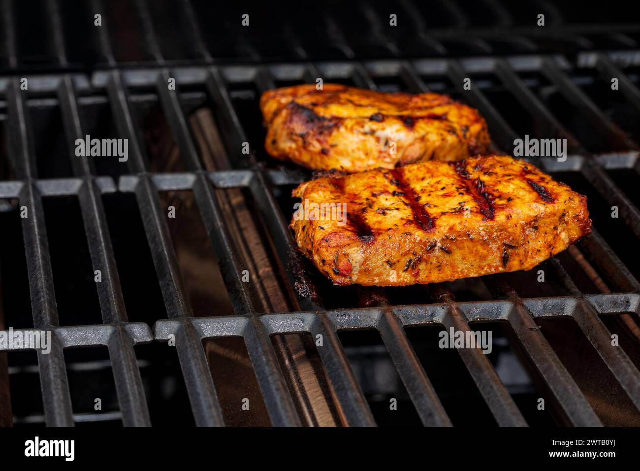 Schweinekoteletts kochen auf Gasgrill. Grill im Freien, Lebensmittelsicherheit und Kochtemperatur-Konzept. Stockfoto