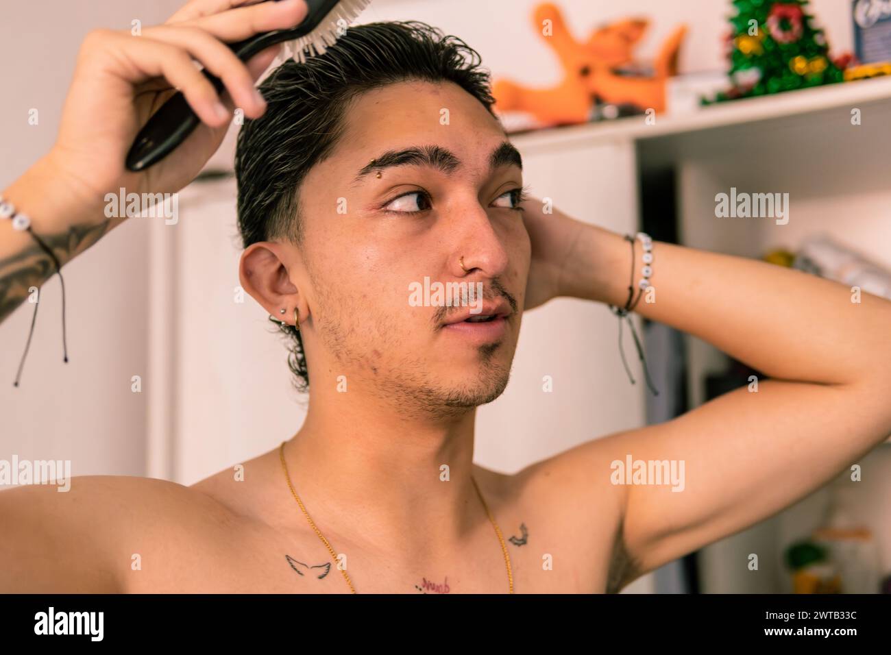 Eine Nahaufnahme eines jungen Latino-Mannes, der zu Hause sein nasses Haar mit einem Kamm pflegt Stockfoto