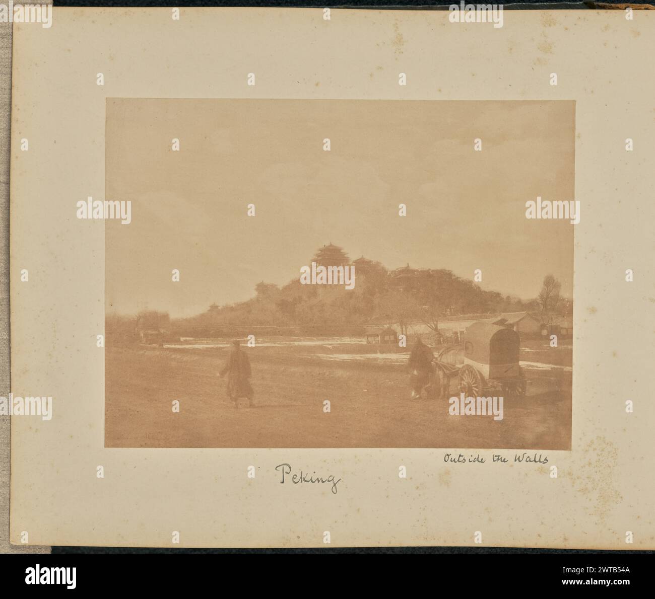 Außerhalb der Wände. Peking. Thomas Child, Fotograf (Britisch, 1841–1898) 1870–1880 Blick auf eine Reihe von Palastgebäuden, die auf einem Hügel gebaut wurden, aus der Ferne. Das größte Gebäude krönt den Hügel, während kleinere pavillonartige Strukturen entlang des Hügels verstreut sind. Im Vordergrund sind zwei Männer zu sehen, von denen einer neben einem überdachten Wagen steht. (Recto, Print) unten links, mit der Negativbeschriftung, schwarz: 'Foto [teilweise zugeschnitten, unterhalb der Signatur]'; (Recto, Mount) unten in der Mitte, in schwarzer Tinte: 'Peking'; unten rechts, in schwarzer Tinte: 'Außerhalb der Wände'; Stockfoto