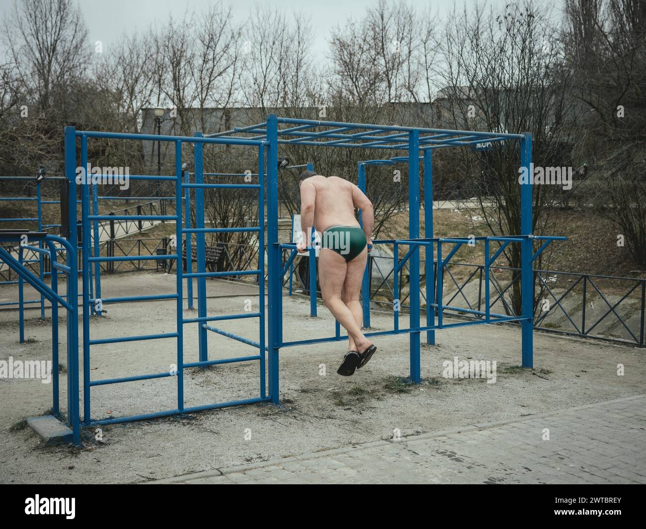 Ein Mann, der in einer Badeanstalt im Severno Saltivka-Viertel Pull-ups macht. Die Nachbarschaft wurde durch russische Raketen weitgehend zerstört Stockfoto
