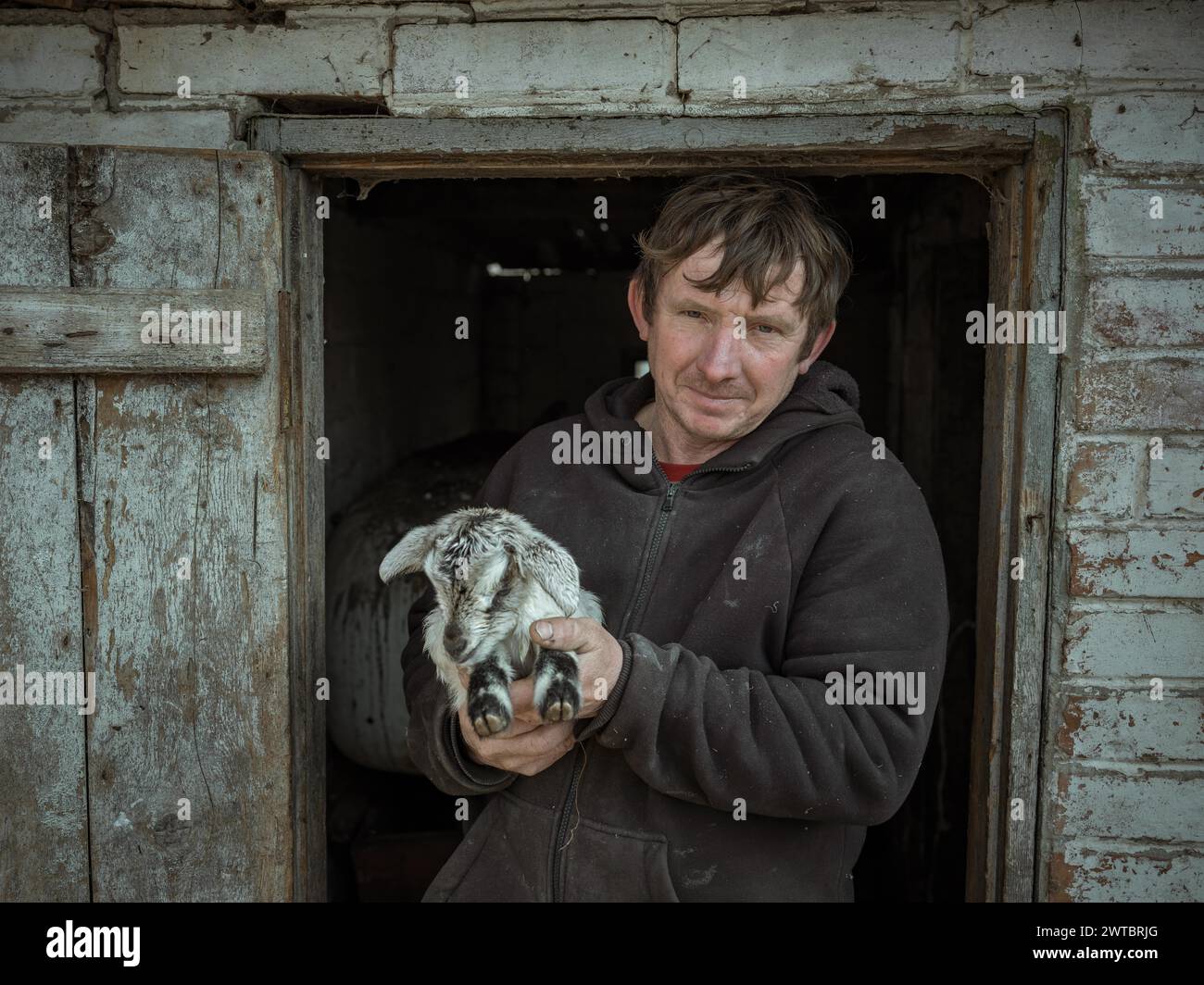 Vova, 46 Jahre alt, Bauer aus Borschchiwka mit einer Ziege. Das Dorf stand sechs Monate lang unter russischer Besatzung. Viva und seine Familie versteckten sich auf dem Stockfoto
