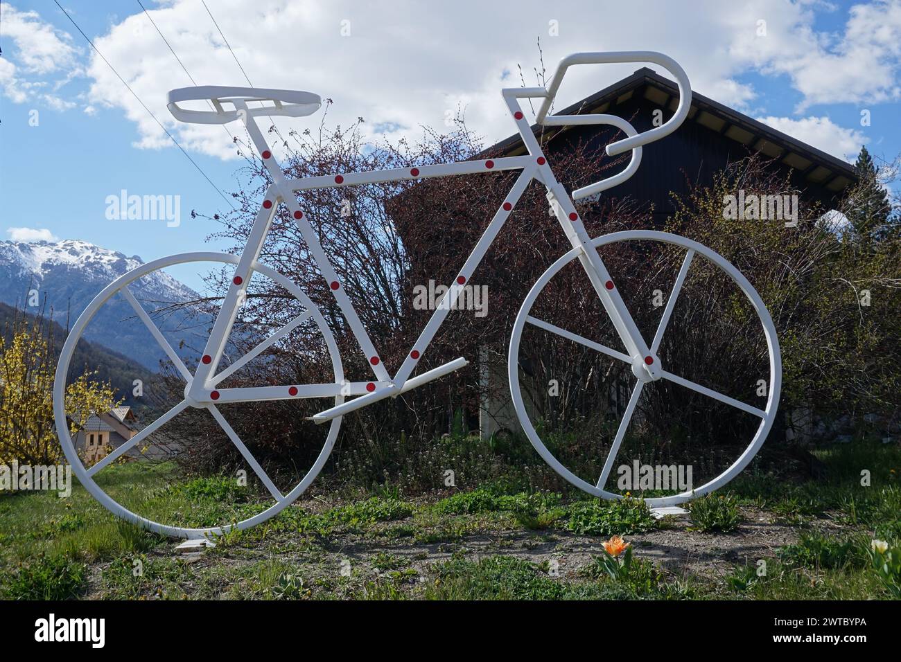 Nahaufnahme eines riesigen weißen Metallfahrrads mit roten Polka-Punkten am Kreisverkehr in briancon, alpen, frankreich Stockfoto