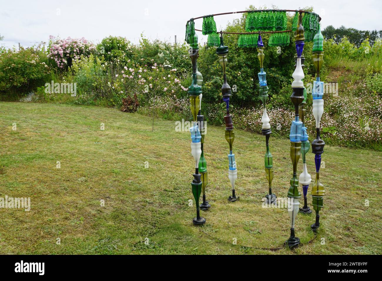 Nahaufnahme auf einer runden Struktur aus Metallstäben und bunten recycelten Flaschen als Kunstwerk im Garten in frankreich Stockfoto