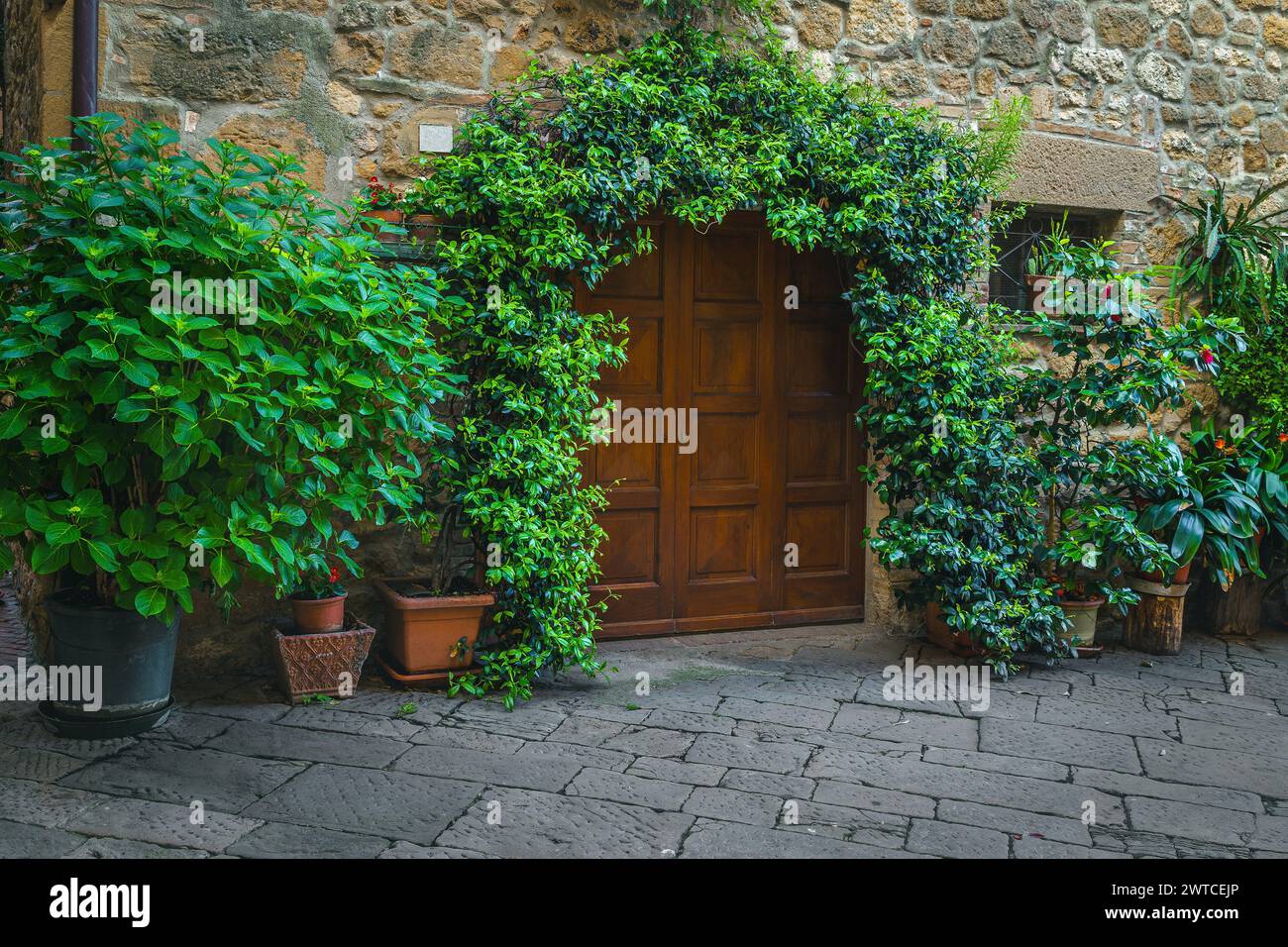 Gepflasterte Straße und ordentliches altes Steinhaus mit dekoriertem Eingang, Toskana, Europa Stockfoto
