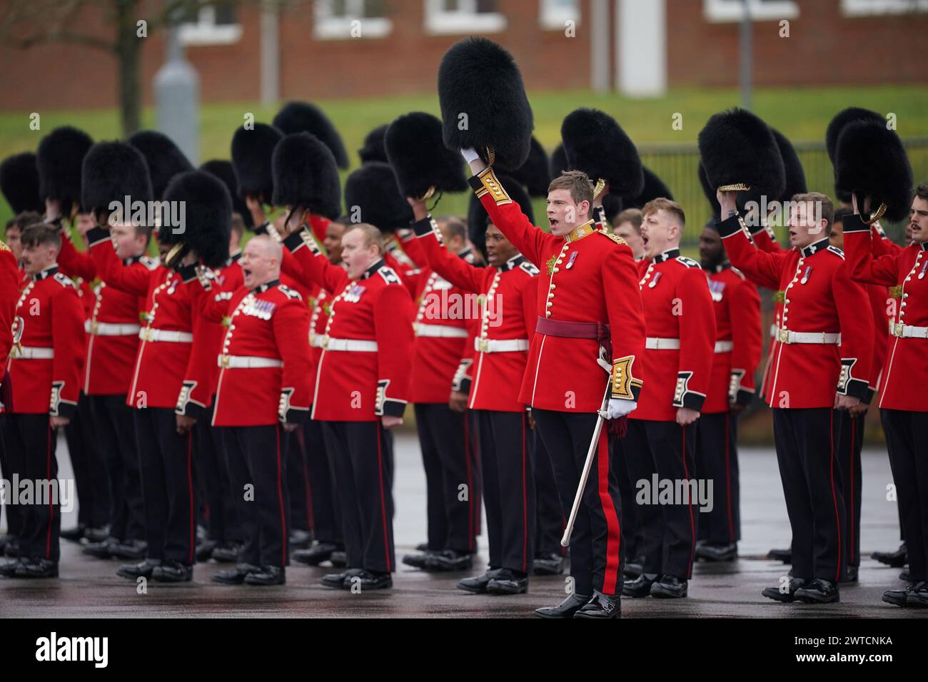 Die irischen Wachmänner heben ihre Kopfbedeckung an, um während einer St. Patrick's Day-Parade auf dem Parade Square in den Mons Barracks in Aldershot zu jubeln. Bilddatum: Sonntag, 17. März 2024. Stockfoto
