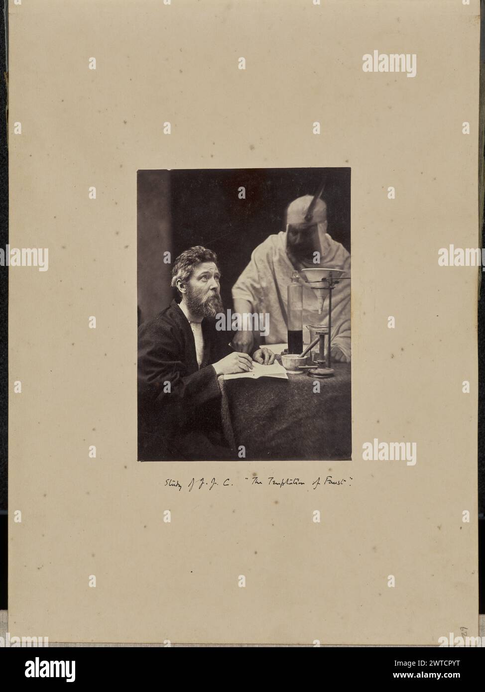 Die Versuchung von Faust. Sir John Joscelyn Coghill, Fotograf (irisch, 1826–1905), etwa 1865 Mann, der an einem Tisch sitzt und einen Stift an Papier hält. Ein zweiter Mann, der einen Kittel und Schutzhelm trägt, steht neben ihm. Chemische Geräte, darunter Mörtel und Pissel, Trichter und Becher, werden auf dem Tisch vor dem Mann in Schutzausrüstung aufgestellt. Unten in der Mitte, unten im Bild, schwarze Tinte in Patrick Coghills Hand: "Studie von J. J. C. [Raum] die Versuchung von Faust." Unten rechts, Bleistift: „62“; Stockfoto