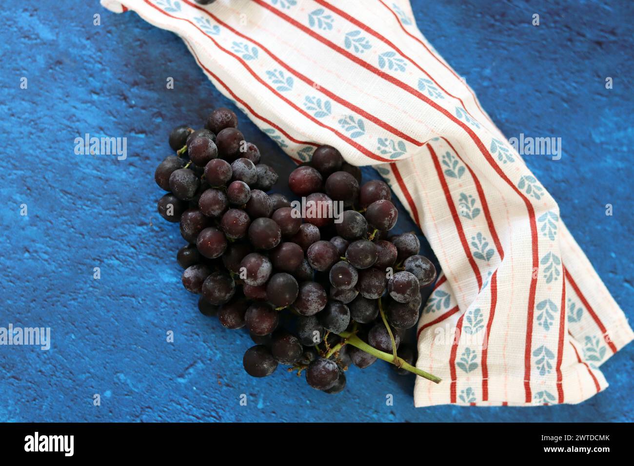 Ein Haufen schwarzer Trauben auf einer Serviette auf blauem Hintergrund Stockfoto