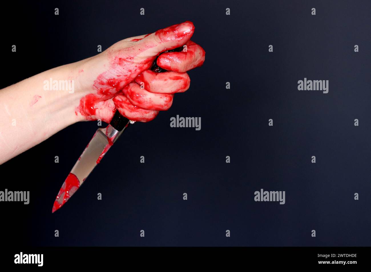 Blutige Hand, die ein Messer mit Blut auf schwarzem Hintergrund hält. Mordkonzept häuslicher Gewaltmissbrauch Stockfoto