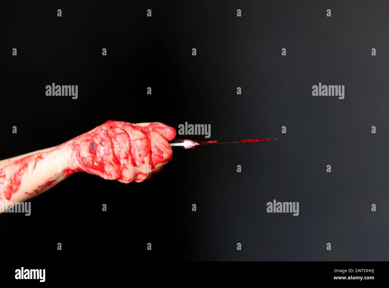 Blutige Hand, die ein Messer mit Blut auf schwarzem Hintergrund hält. Mordkonzept häuslicher Gewaltmissbrauch Stockfoto