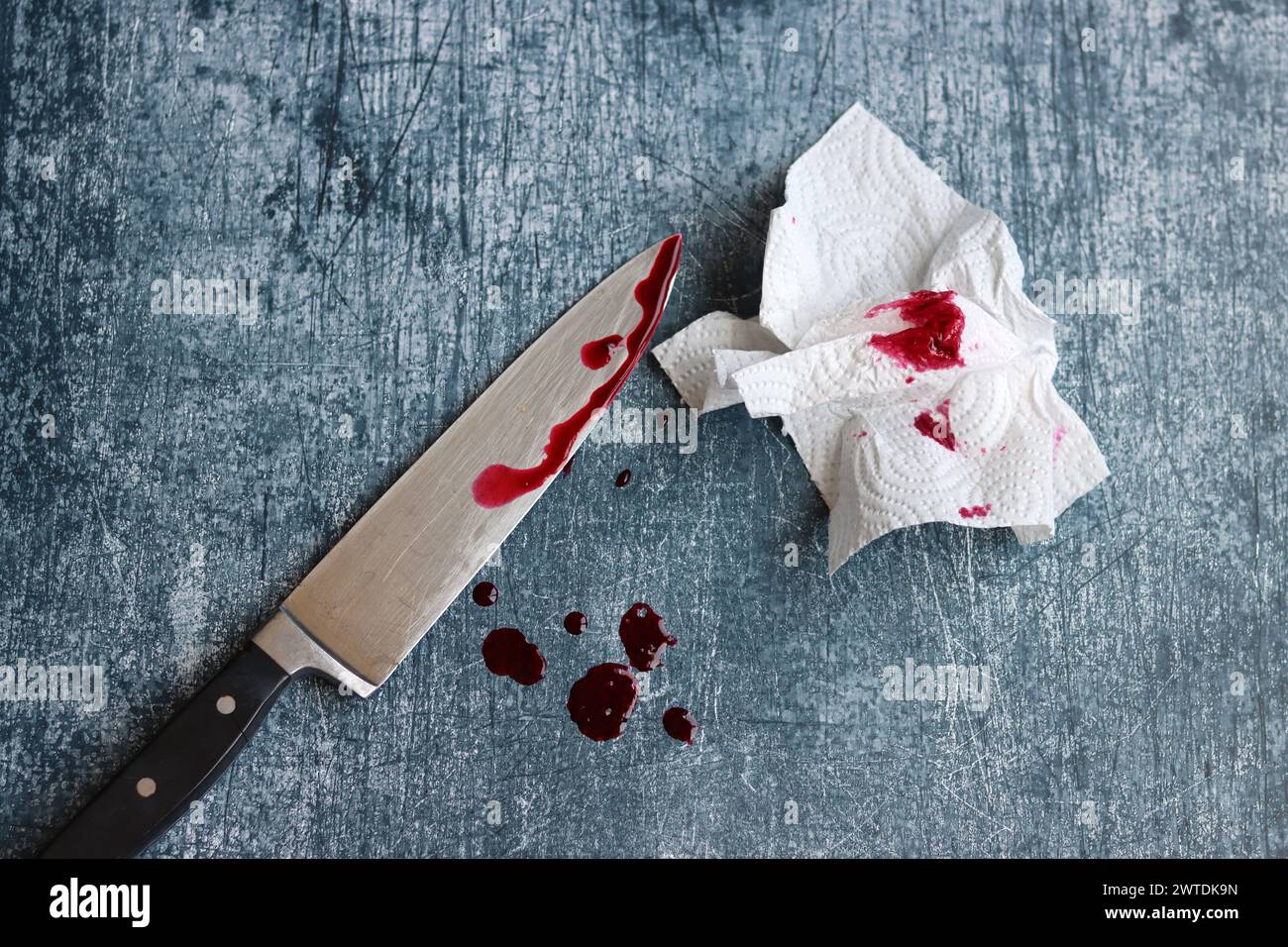 Verdammtes großes Messer auf grundigem grauen Hintergrund mit Kopierraum. Bluttropfen auf rostigem Hintergrund. Häusliche Gewalt. Stockfoto