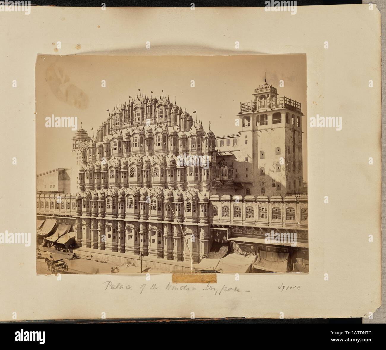Palast der Winde - Jeypore. Unbekannt, Fotograf etwa 1866–1870 View of the Hawa Mahal, oder Palace of the Winds, ein palastartiger Komplex mit einer kunstvollen Fassade und abgeschirmten Fensterbuchten. Im unteren linken Bereich des Bildes sind eine Reihe von Personen und ein Pferdewagen zu sehen. (Recto, bedruckt) unten links, im negativ beschriftet, weiß: '130'; (Recto, Mount) unten in der Mitte, Bleistift: 'Palast der Winde - Jeypore -'; unten rechts, mit Bleistift, in einer anderen Hand: 'Jypore'; (rückseitig, Mount) unten links, Bleistift: 'A48.134'; Stockfoto
