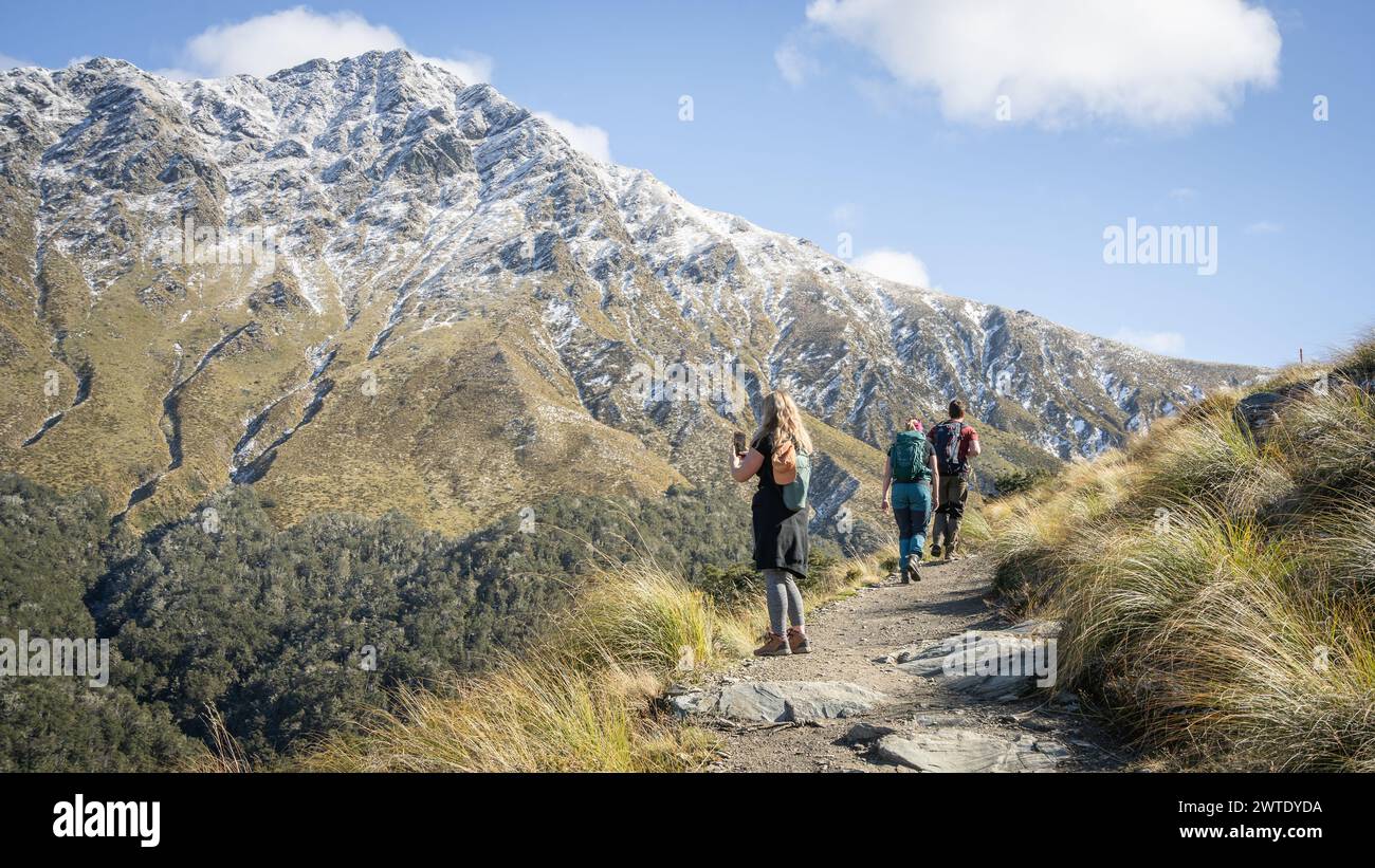 Wanderer, die am sonnigen Herbsttag in Richtung schneebedeckter Berge wandern, Neuseeland Stockfoto