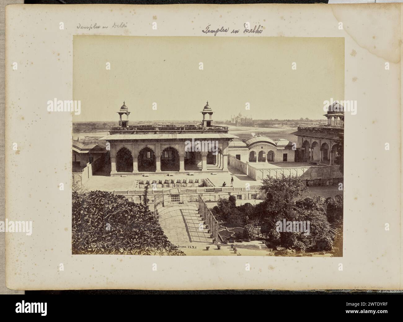 Agra; das Fort, der Palast von Akbar mit dem Taj in der Ferne. Samuel Bourne, Fotograf (1834–1912) 1865–1866 Ansicht eines inneren Abschnitts des Agra Fort mit Blick auf das Taj Mahal im Hintergrund. Ein Garten mit Pflanzen verschiedener Arten ist im Vordergrund zu sehen, während der Khas Mahal, ein Pavillon mit gewellten Bögen und zwei Chattris, oder dekorative Kuppelpavillons, auf seinem Dach in der Mitte zu sehen sind. Zwei Männer sind in der Nähe eines versunkenen Brunnens vor dem Pavillon zu sehen. (Recto, Print) unten in der Mitte, negativ beschriftet: '1221'; (Recto, Mount) oben links, Zoll Stockfoto Agra; das Fort, der Palast von Akbar mit dem Taj in der Ferne. Samuel Bourne, Fotograf (1834–1912) 1865–1866 Ansicht eines inneren Abschnitts des Agra Fort mit Blick auf das Taj Mahal im Hintergrund. Ein Garten mit Pflanzen verschiedener Arten ist im Vordergrund zu sehen, während der Khas Mahal, ein Pavillon mit gewellten Bögen und zwei Chattris, oder dekorative Kuppelpavillons, auf seinem Dach in der Mitte zu sehen sind. Zwei Männer sind in der Nähe eines versunkenen Brunnens vor dem Pavillon zu sehen. (Recto, Print) unten in der Mitte, negativ beschriftet: '1221'; (Recto, Mount) oben links, Zoll Stockfoto