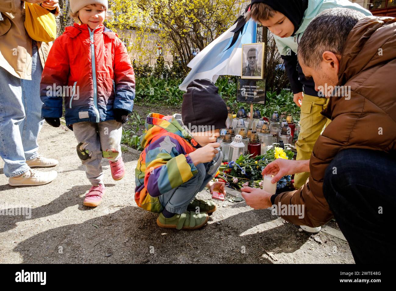 Krakau, Polen, 17. März 2024. Eine Familie zündet am dritten Tag der russischen Präsidentschaftswahlen am Mittag vor dem russischen Konsulat in Krakau ein Licht für Alexej Nawalny an. Der russische Oppositionsführer, der vor kurzem im Gefängnis starb, Alexej Nawalny und dann seine Frau Julia Nawalna, riefen die Opposition an, um am 17. März Mittag zu den Wahlumfragen zu kommen, um dem russischen Präsidenten Wladimir Putin die Zahl der Gegner seiner Regierung zu zeigen. Es ist illegal und gefährlich, gegen die Regierung in Russland zu protestieren, deshalb schlug Nawalny vor, sich zu einem bestimmten Zeitpunkt bei den Wahlen zu versammeln. Stockfoto