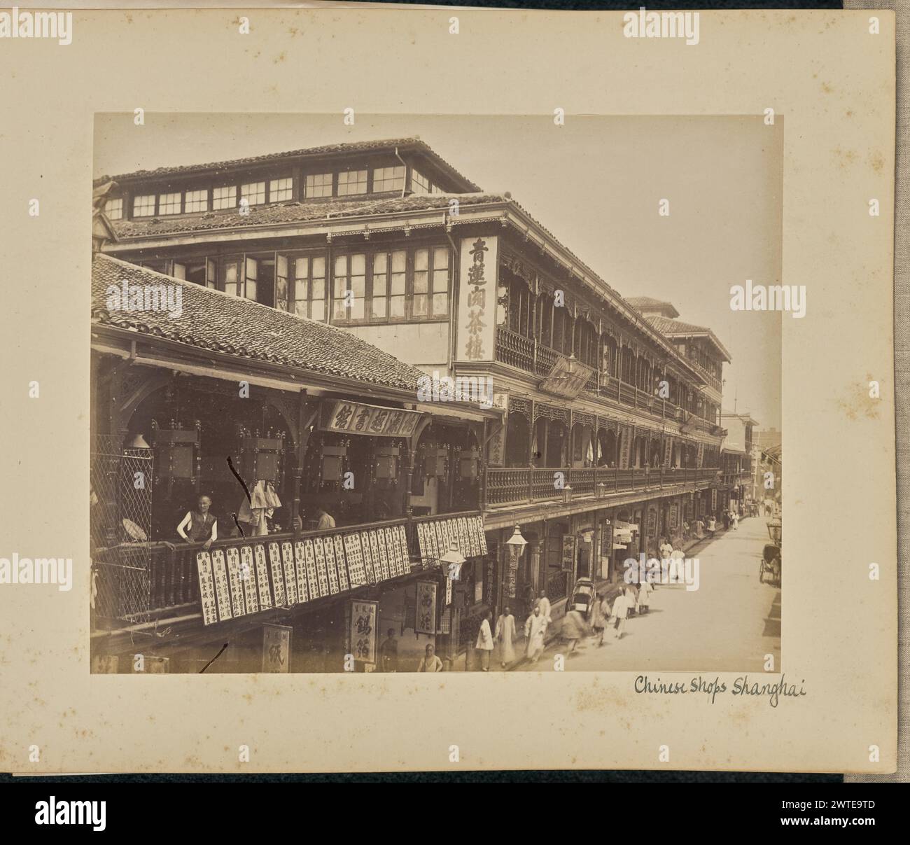 Chinesische Geschäfte. Shanghai. Unbekannt, Fotograf 1890–1900 Ansicht des Qinglian GE Tea House, manchmal als Green Lotus Tea House identifiziert, ein dreistöckiges Gebäude an der Fourth Avenue in Shanghai, heute Fuzhou Road. Das Gebäude verfügt über Balkone in den oberen Stockwerken. Daneben steht ein zweistöckiges Gebäude, auf dem man auf dem Balkon einen Mann sehen kann, der in den linken Bereich des Bildes blickt. Schilder sind an verschiedenen Ladenfronten entlang der Straße zu sehen. (Recto, Mount) rechts unten, in schwarzer Tinte: 'Chinese Shops Shanghai'; Stockfoto