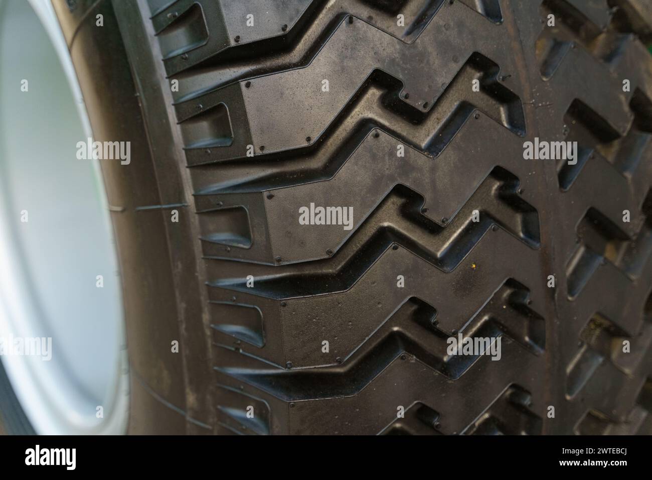 Detailansicht eines an einem Fahrzeug montierten Reifens mit Profil und Seitenwand. Der Reifen ist schmutzig, was darauf hinweist, dass er kürzlich verwendet wurde. Stockfoto