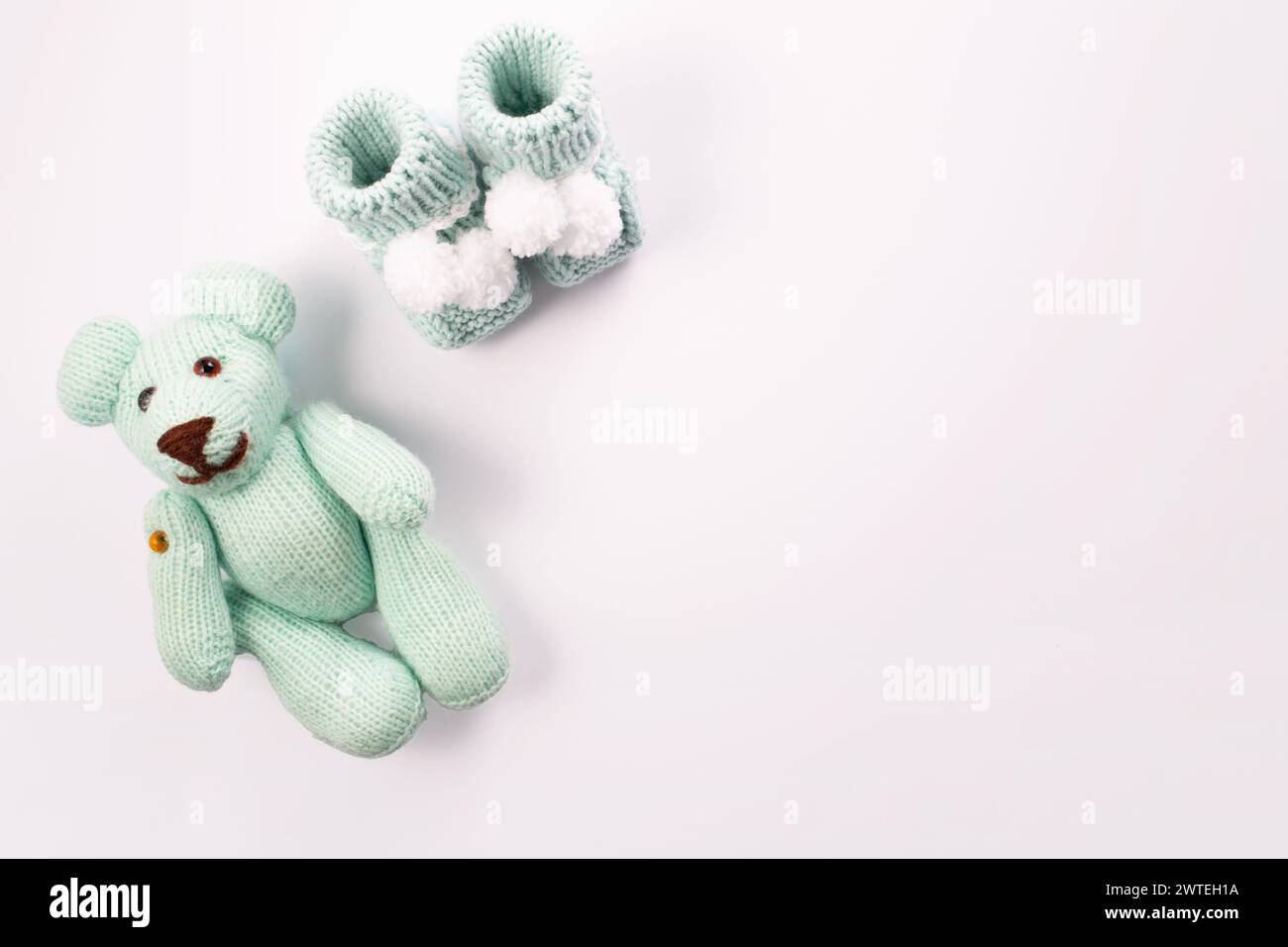 Babysocken und Teddybär auf weißem Hintergrund. Die Geburt eines Jungen. Grußkarte.Ankündigung der Schwangerschaft. Flach, Draufsicht Stockfoto