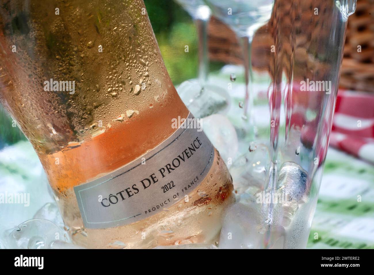 Cotes de Provence French Rosé 2022 Weinflasche mit Etikett auf Eis im Weinkühler auf einem Picknicktisch im Freien mit Korbkorb dahinter Stockfoto