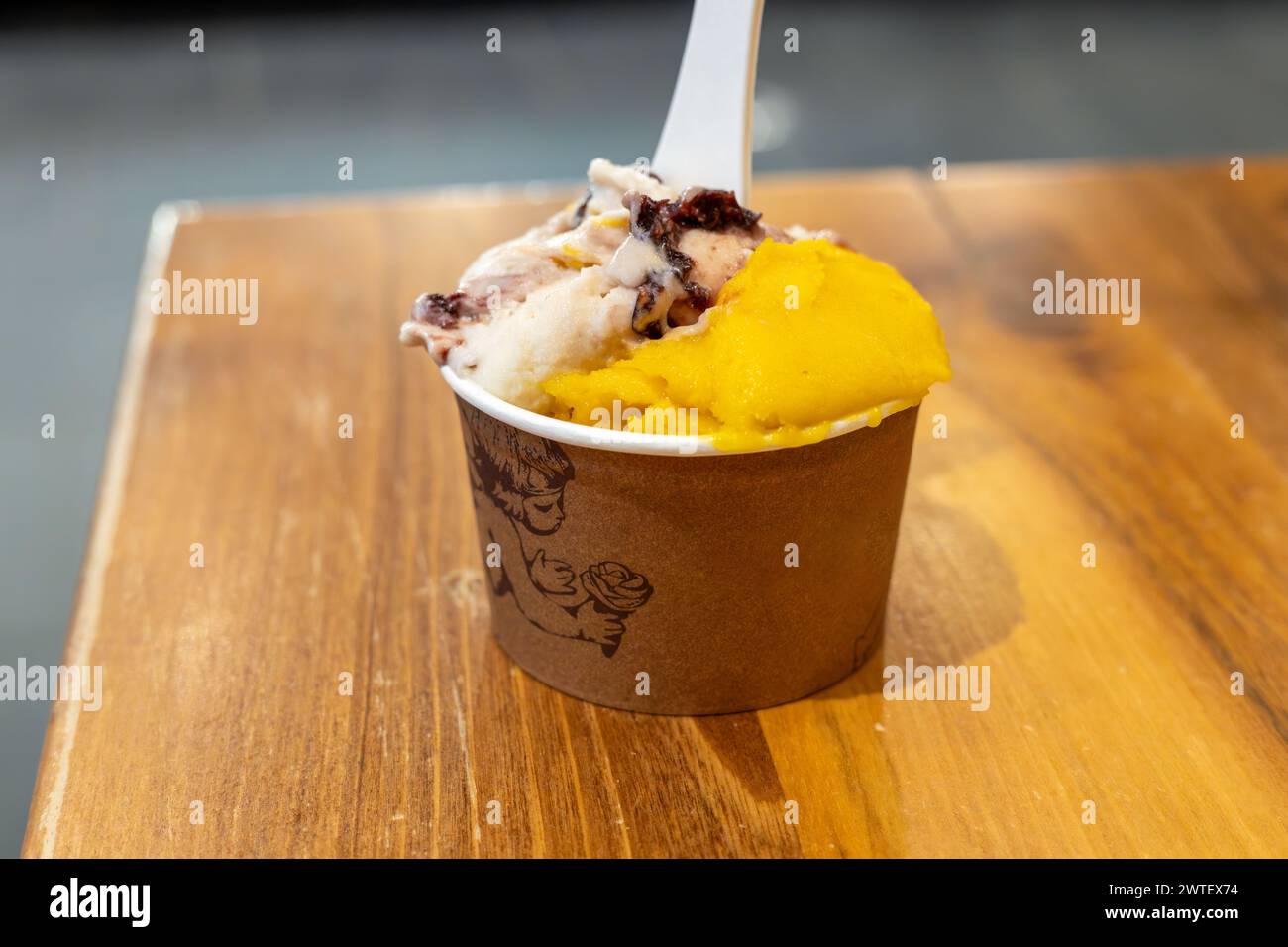 Mango- und Kirscheis im Einwegbecher auf dem Tisch. Italienische Gelateria. Natürliches frisches Eis. Stockfoto