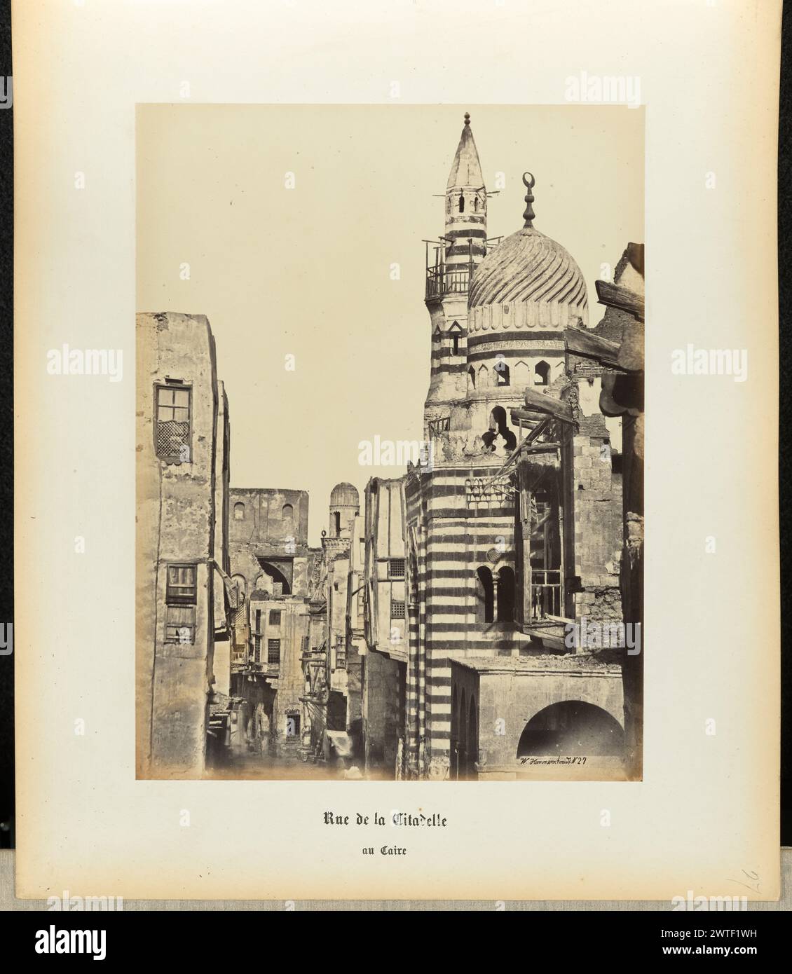 Citadel Road. Wilhelm Hammerschmidt, Fotograf (deutsch, geb. Preußen, gestorben 1869) 1860er Jahre Ein Blick auf eine enge Straße in Kairo, die von hohen Gebäuden und einer horizontal gestreiften Kuppelmoschee auf der rechten Seite gesäumt ist. (Recto) oben rechts, in Bleistift: "27"; (rückseitig) unten links, in Bleistift: "A 32 39 (Hamm)"; Stockfoto Citadel Road. Wilhelm Hammerschmidt, Fotograf (deutsch, geb. Preußen, gestorben 1869) 1860er Jahre Ein Blick auf eine enge Straße in Kairo, die von hohen Gebäuden und einer horizontal gestreiften Kuppelmoschee auf der rechten Seite gesäumt ist. (Recto) oben rechts, in Bleistift: "27"; (rückseitig) unten links, in Bleistift: "A 32 39 (Hamm)"; Stockfoto