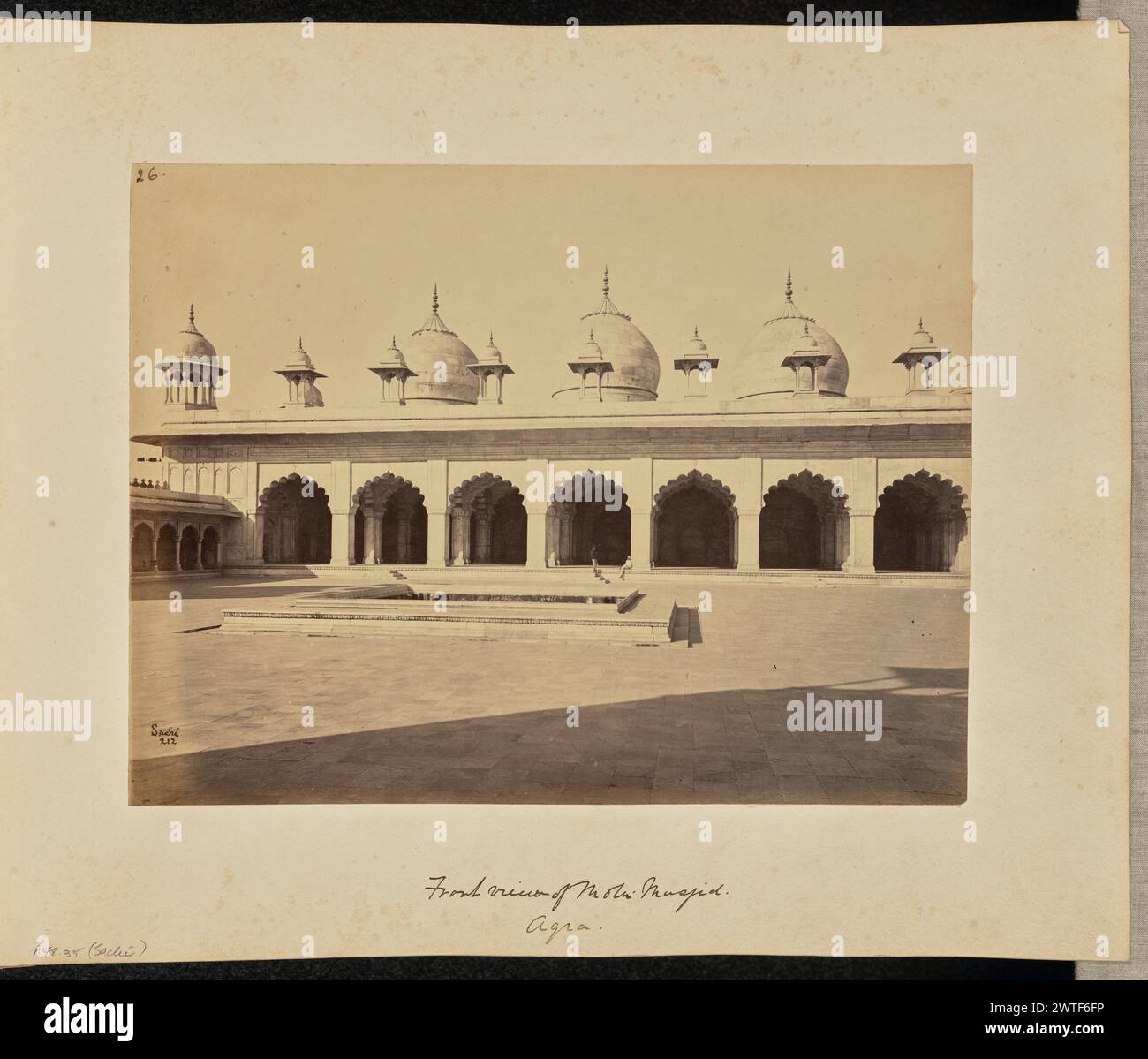 Vorderansicht von Moti Musjid. Agra. John Edward Saché, Fotograf (preußisch oder britisch, geb. Preußen, 1824–1882) um 1868 Blick auf einen offenen Platz vor dem Motee, oder Moti, Masjid oder der Perlenmoschee, mit seinen mehreren gewellten Bögen, großen Kuppeln und Chattris oder dekorativen Kuppelpavillons. Die Moschee steht im Vordergrund vor einem versunkenen Brunnen oder Wassertank. Zwei Männer sind unter einem der gewellten Bögen zu sehen. (Recto, bedruckt) oben links, in brauner Tinte: '26.'; unten links, im negativ beschriftet: '212'; (Recto, Mount) unten links, in Bleistift: 'A48.35 (Saché)'; unten in der Mitte, in brauner Tinte Stockfoto Vorderansicht von Moti Musjid. Agra. John Edward Saché, Fotograf (preußisch oder britisch, geb. Preußen, 1824–1882) um 1868 Blick auf einen offenen Platz vor dem Motee, oder Moti, Masjid oder der Perlenmoschee, mit seinen mehreren gewellten Bögen, großen Kuppeln und Chattris oder dekorativen Kuppelpavillons. Die Moschee steht im Vordergrund vor einem versunkenen Brunnen oder Wassertank. Zwei Männer sind unter einem der gewellten Bögen zu sehen. (Recto, bedruckt) oben links, in brauner Tinte: '26.'; unten links, im negativ beschriftet: '212'; (Recto, Mount) unten links, in Bleistift: 'A48.35 (Saché)'; unten in der Mitte, in brauner Tinte Stockfoto