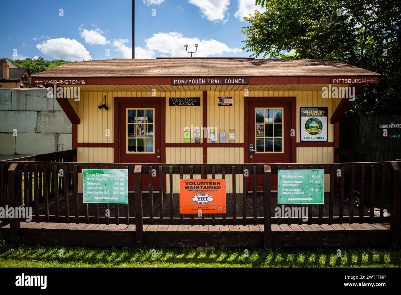 Der charmante, alte gelbe Bahnhof liegt am Youghiogheny River Trail in Pennsylvania und besticht durch seine roten Türen und seine informative Distanz Stockfoto