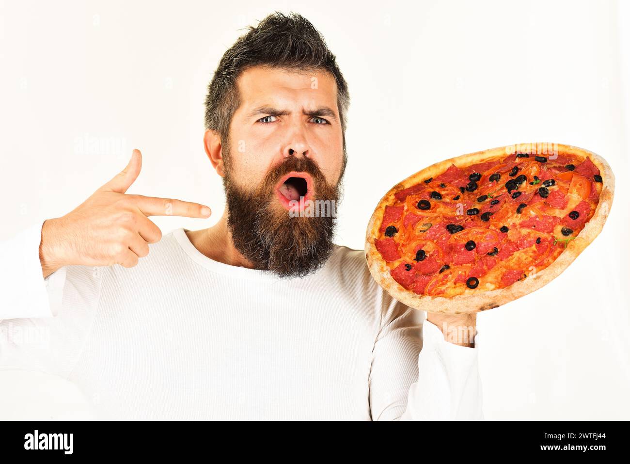 Pizza Zeit. Mittag- oder Abendessen. Fastfood. Überraschter bärtiger Mann, der mit dem Finger auf leckere Pizza zeigt. Lieferservice. Gutaussehender Mann mit Bart in Casual Stockfoto