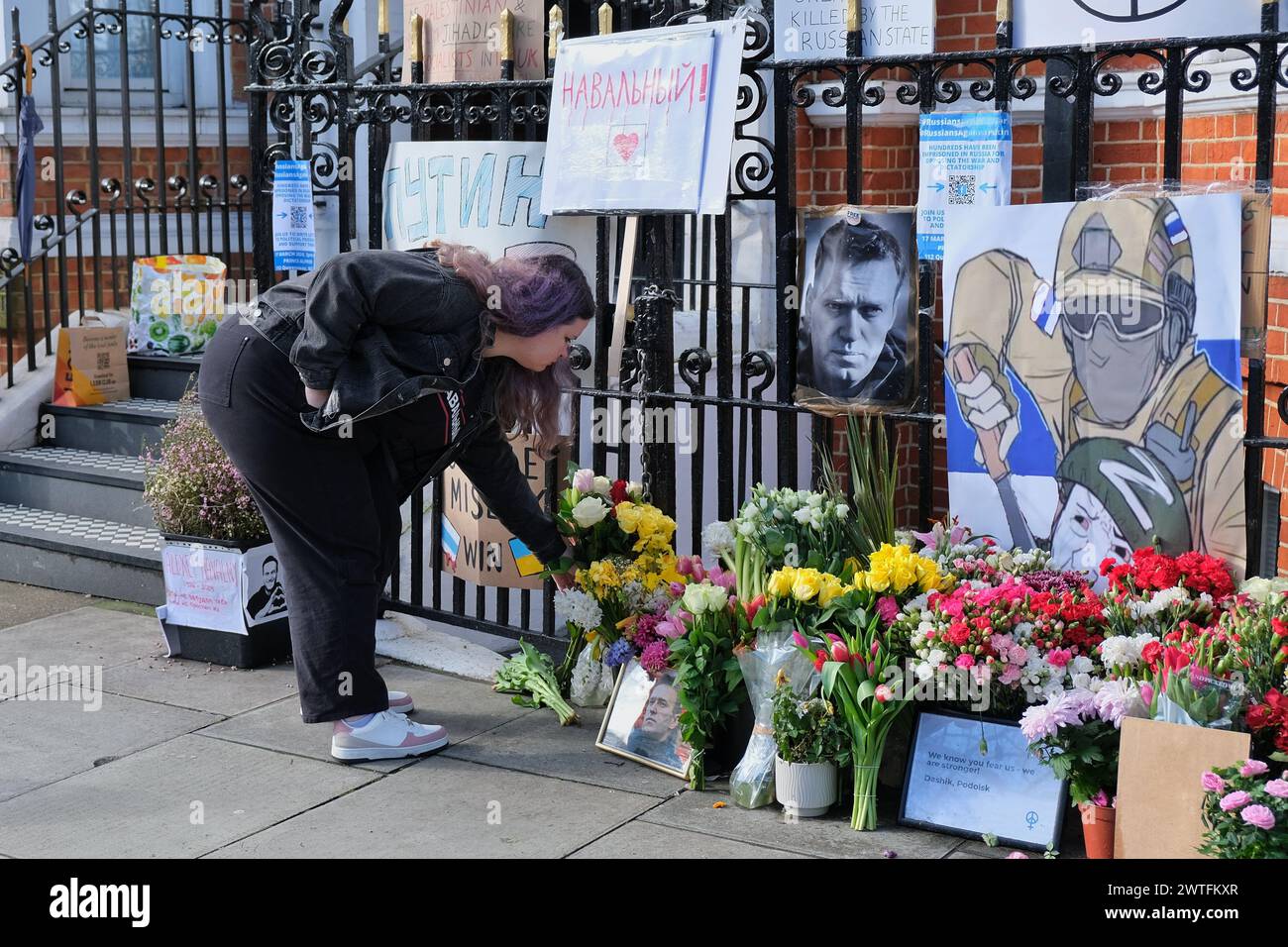 London, Großbritannien. März 2024. Eine Frau hinterlässt Blumen an der Gedenkstätte der Unterstützer für den russischen Oppositionsführer Alexej Nawalny. Tausende von Wählern kamen in die russische Botschaft in Kensington, einige Wähler standen vier Stunden lang an, bevor sie ihre Stimme abgeben. Viele wartende Menschen wurden in der blau-weißen pro-demokratischen Flagge gesehen, als Julia, die Ehefrau des verstorbenen Oppositionsführers Alexej Nawalny, die Wähler dazu drängte, in einem Protest gegen Putin zu erscheinen, während Nawalnys Team Einzelpersonen bat, ihre Stimmzettel zu verderben. Quelle: Eleventh Photography/Alamy Live News Stockfoto