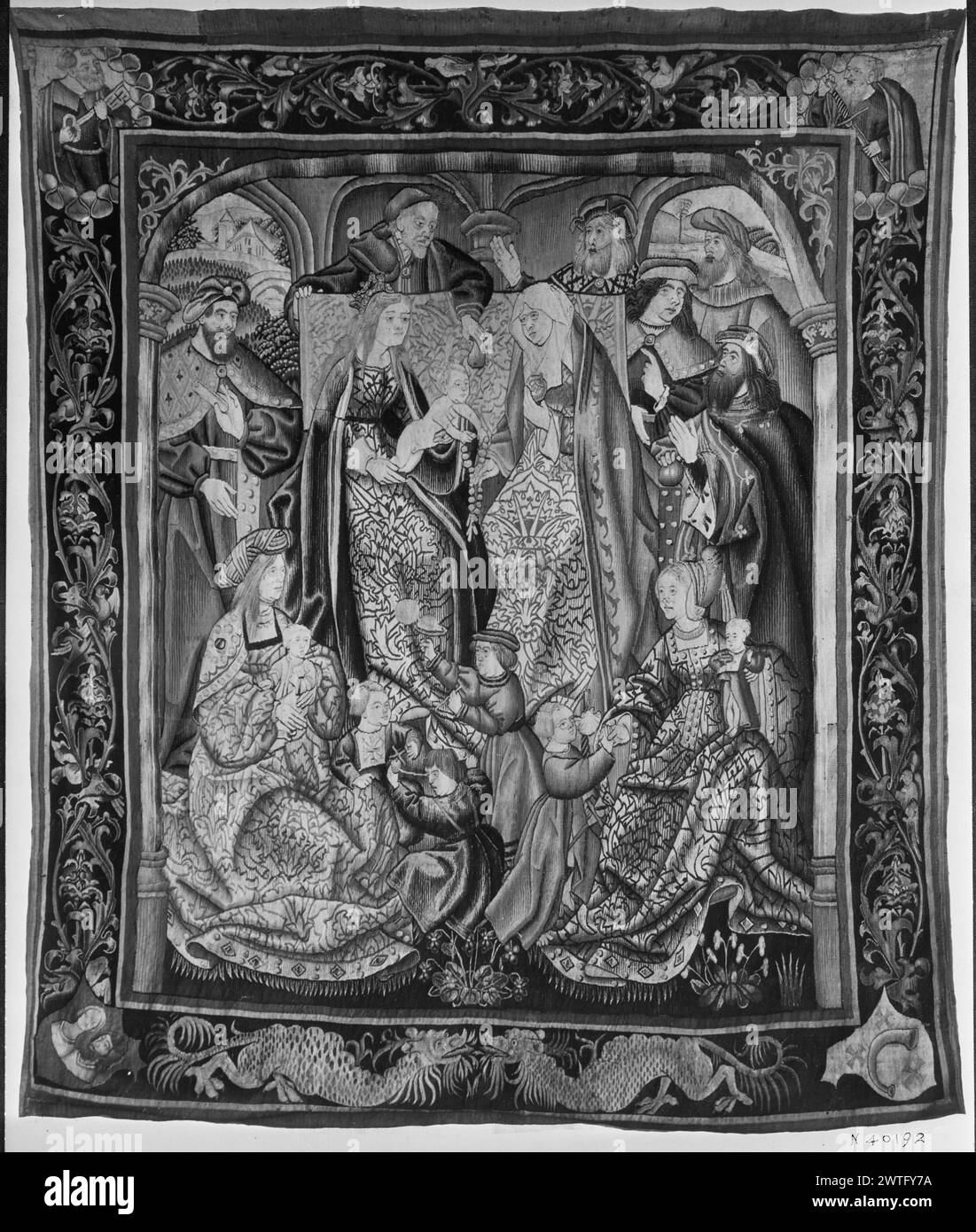 Geburt Christi: Heilige Familie Trinitas terrestris. Unbekannt ca. 1510-1530 Gobelin Materialien/Techniken: Unbekannt Kultur: Southern Netherlands Weaving Center: Unbekannt Besitz Geschichte: Französisch & Co. Auf dem Thron sitzt Christkind auf dem Schoß der Jungfrau Maria und streckt nach dem Rosenkranz, den ihm von der Heiligen überreicht wurde Anne; St. Joseph übergibt die Birne von oben; umgeben von männlichen Figuren, Frauen und Kindern (L, UPR & R BRD), die sich mit Laubstöcken und kleinen Vögeln verflechten; (UPR BRD) Heilige in den Ecken: St. Peter hält Schlüssel (L) und St. Paul (?) Schwert halten (R); (LWR BRD) 2 Drachen von Angesicht zu Angesicht; Wappen Stockfoto