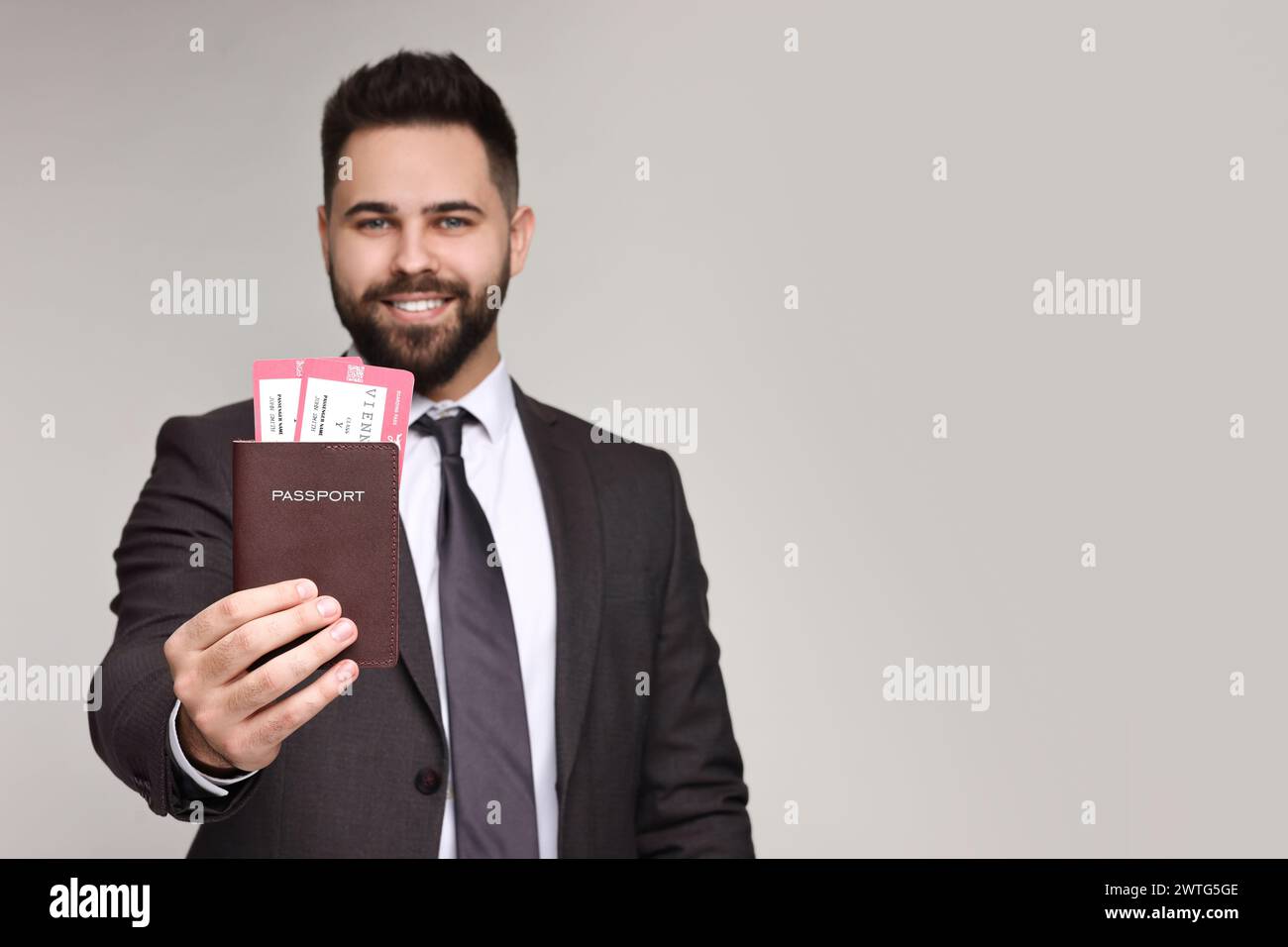 Glücklicher Geschäftsmann, der Reisepass und Tickets auf grauem Hintergrund zeigt, selektiver Fokus. Leerzeichen für Text Stockfoto