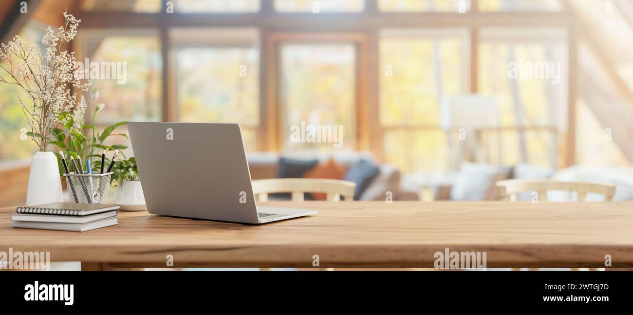 Ein Rückansicht eines Laptops, Bücher und Dekor auf einem Holztisch in einem komfortablen Wohnzimmer des Bauernhauses. Konzept für den Arbeitsplatz zu Hause. 3D-Rendering, Stockfoto