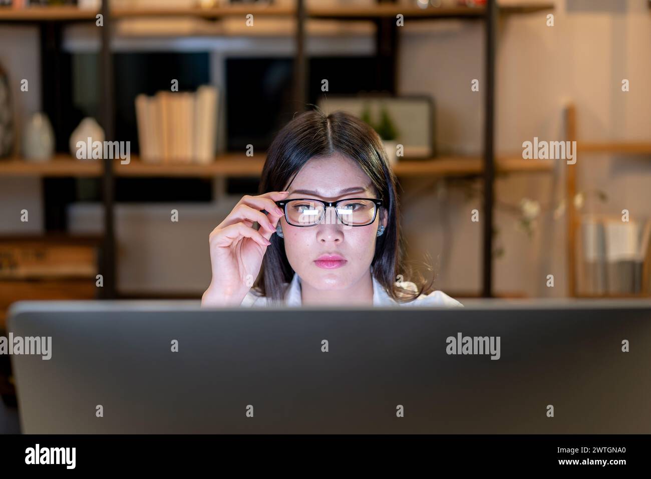Die junge Frau sitzt und starrt auf den Computerbildschirm Stockfoto
