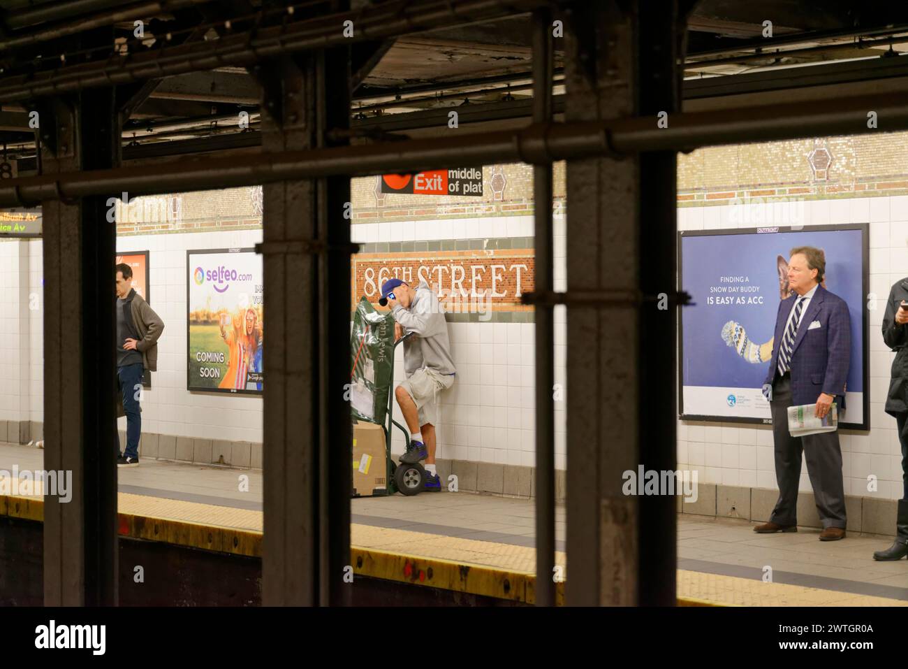 Leute, die auf dem Bahnsteig einer U-Bahnstation neben Werbeplakaten warten, Manhattan, New York City, New York, USA, Nordamerika Stockfoto