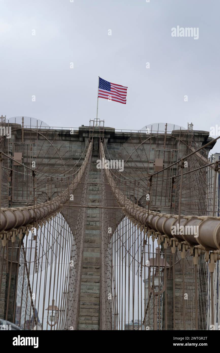 Brooklyn Bridge, vertikale Aufnahme der Spitze einer Brücke mit amerikanischer Flagge an einem bewölkten Tag, Manhattan, New York City, New York, USA, Nordamerika Stockfoto