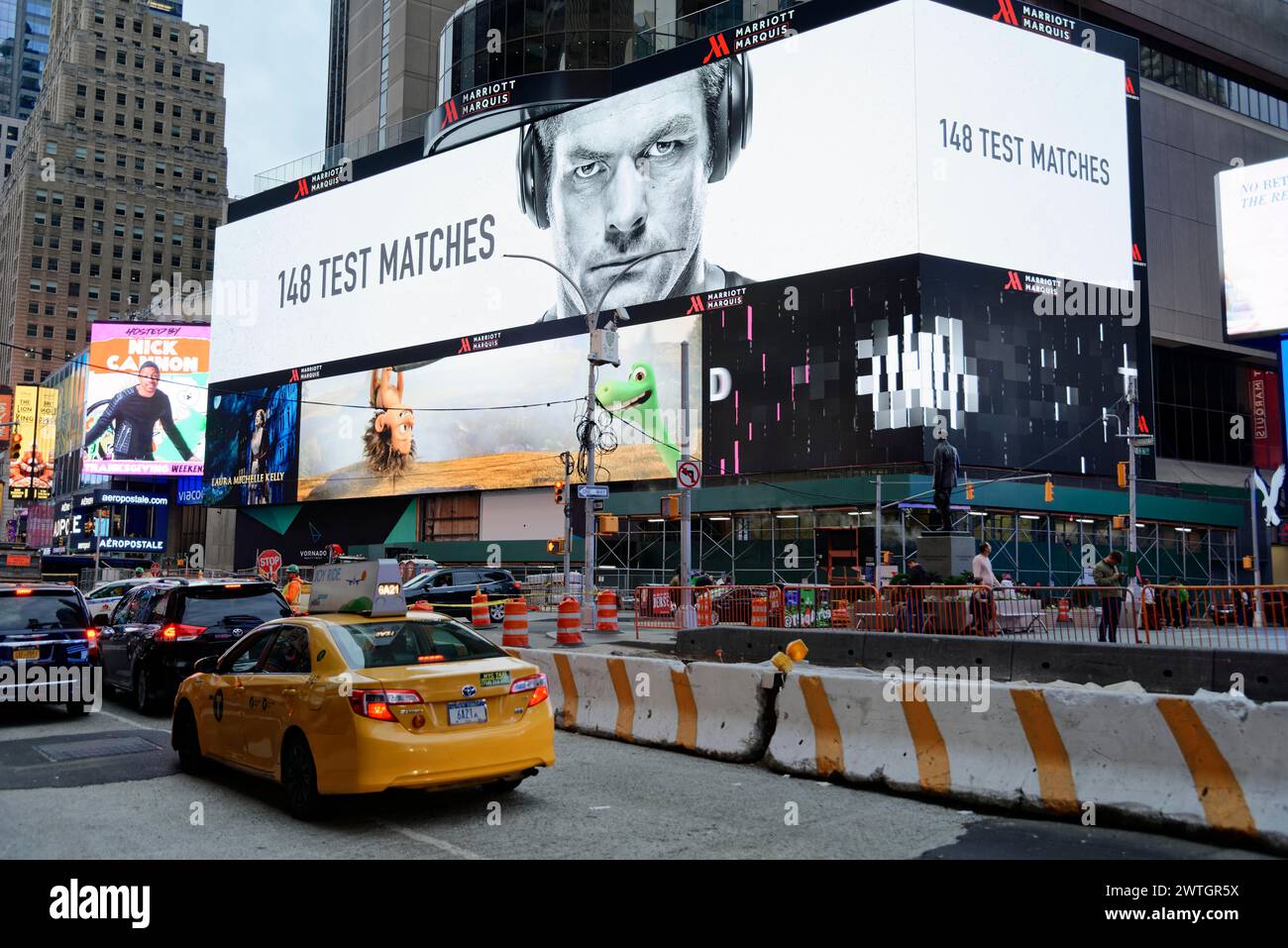 Ein gelbes Taxi fährt an einer mit Werbeplakaten geschmückten Baustelle vorbei, Manhattan, New York City, New York, USA, Nordamerika Stockfoto