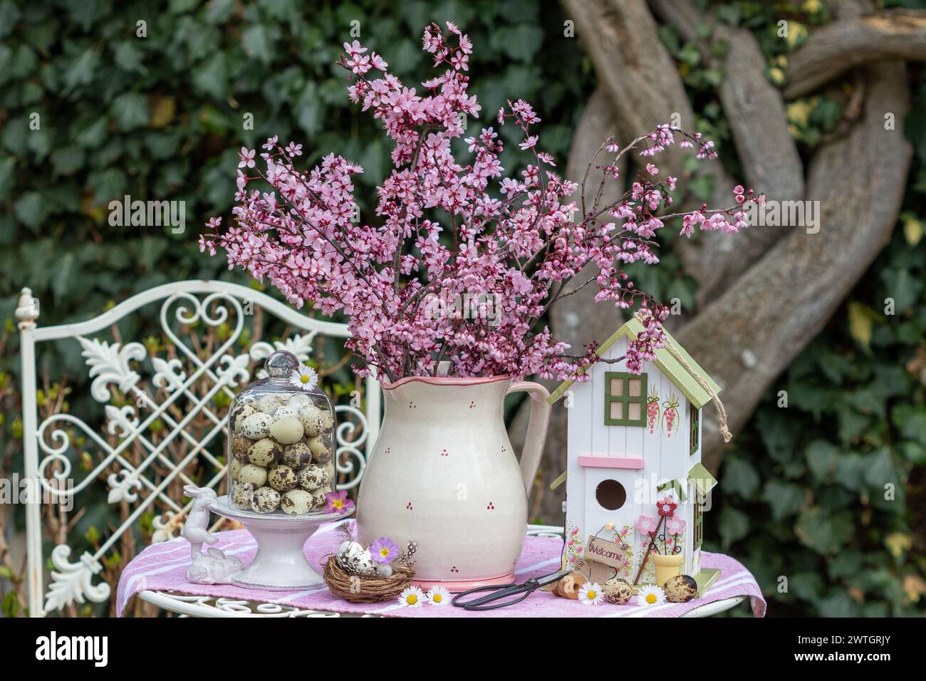Arrangement mit Blumenstrauß aus violetter Pflaume, Vogelhaus und Wachteleiern Stockfoto
