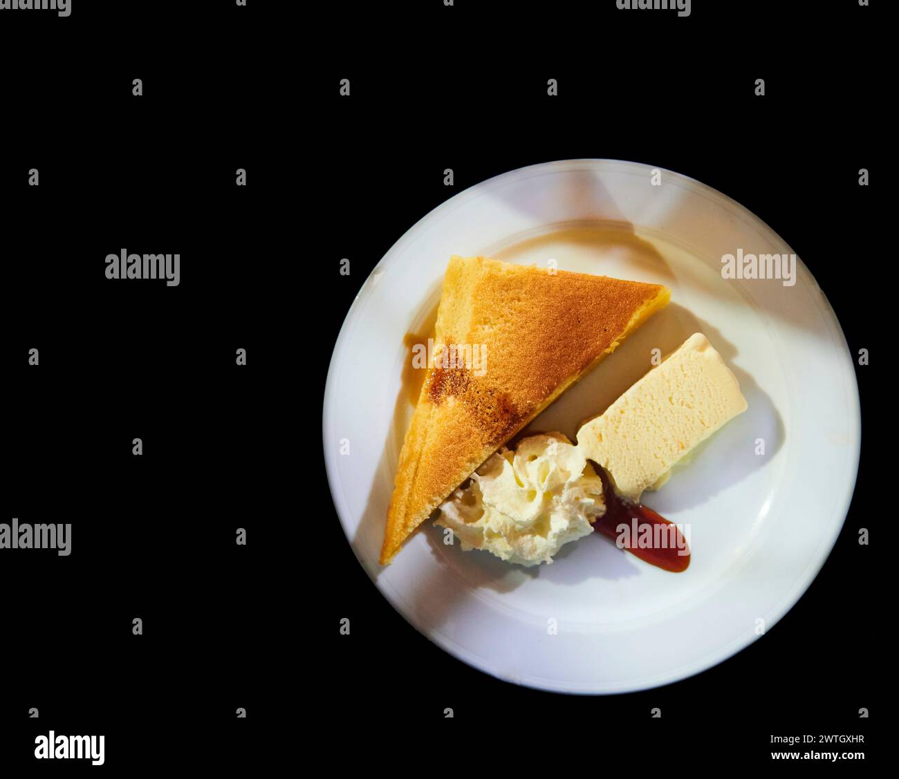 Dessertplatte mit Eis, Rahm und Käsekuchen auf schwarzem Hintergrund Stockfoto