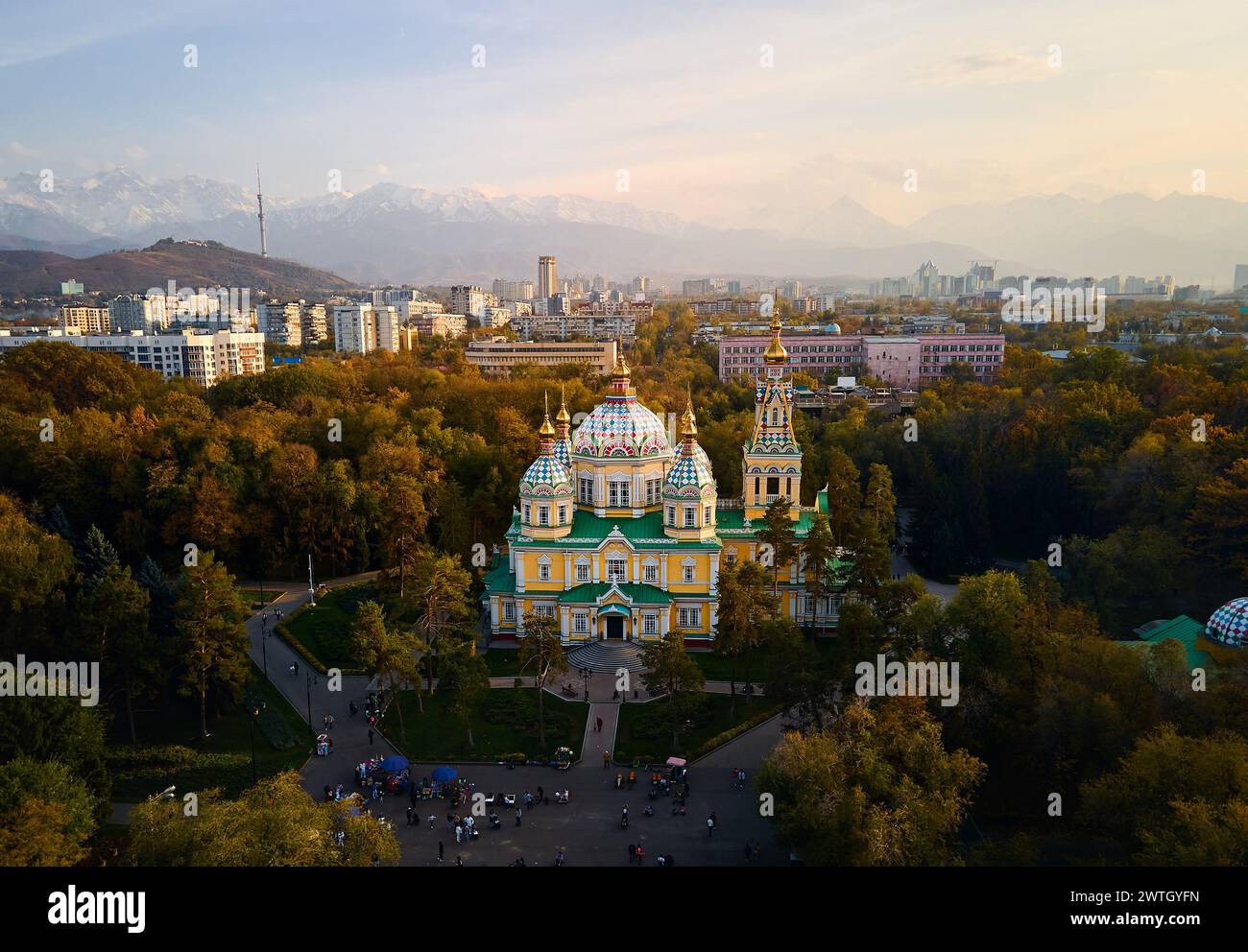 Luftdrohnen-Panorama der Ascension Cathedral Russisch-orthodoxe Kirche und Schneeberge im Hintergrund im Panfilov Park vor Sonnenuntergang Himmel in Almat Stockfoto