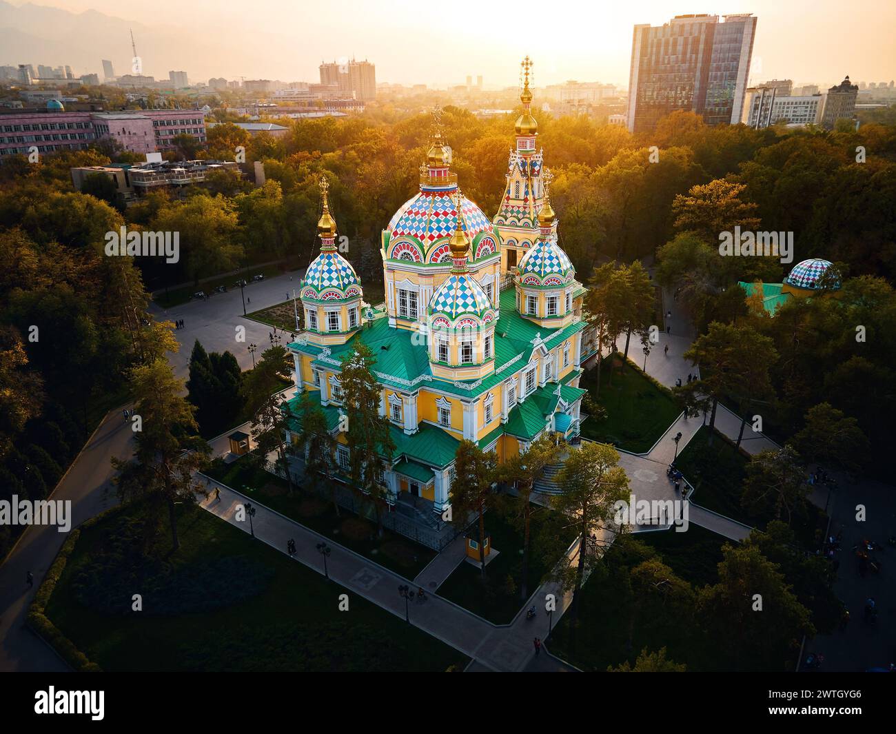 Luftdrohnen-Panorama der Ascension Cathedral Russisch-orthodoxe Kirche und Schneeberge im Hintergrund im Panfilov Park vor Sonnenuntergang Himmel in Almat Stockfoto