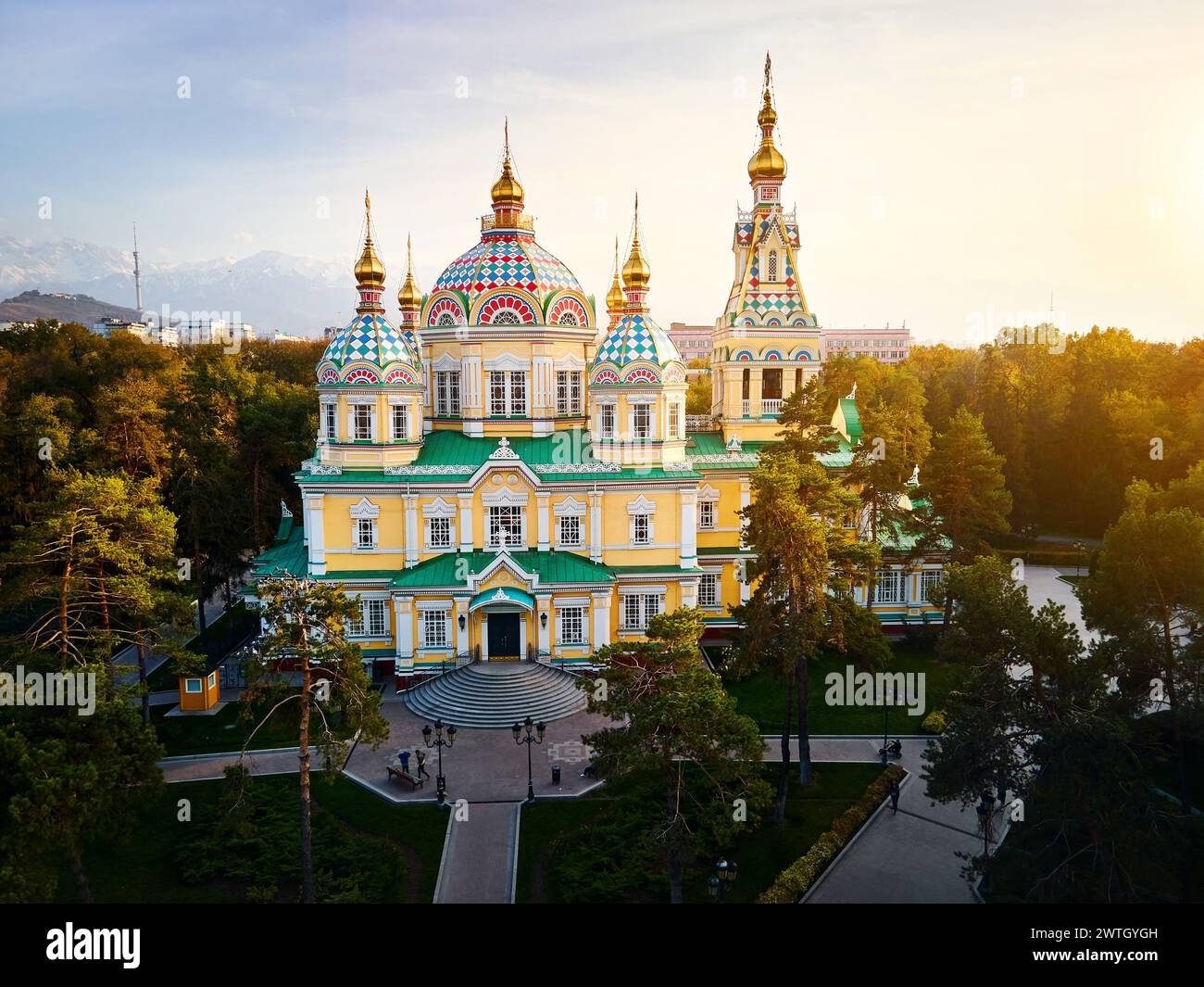 Luftdrohnen-Panorama der Ascension Cathedral Russisch-orthodoxe Kirche und Schneeberge im Hintergrund im Panfilov Park vor Sonnenuntergang Himmel in Almat Stockfoto