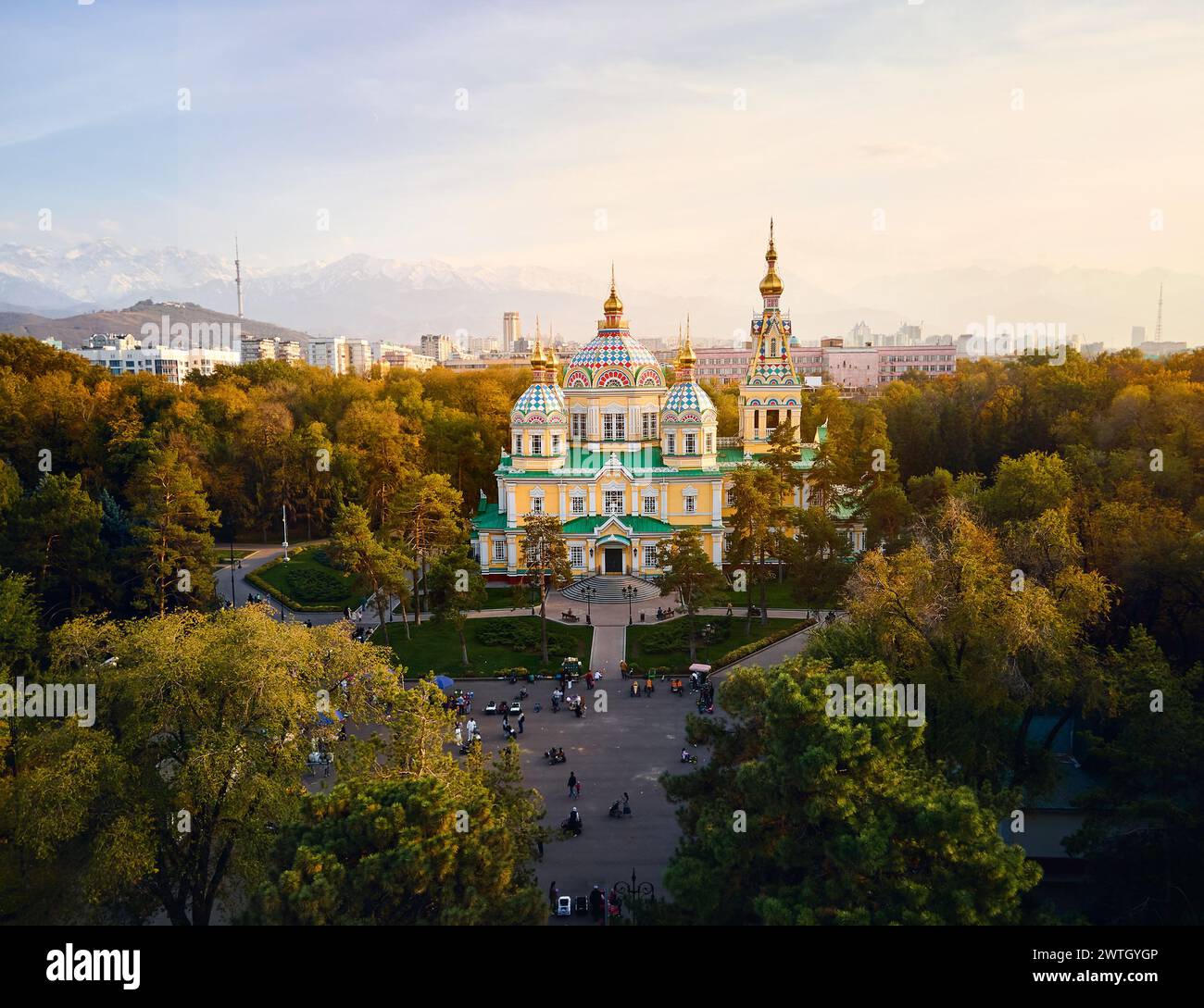 Luftdrohnen-Panorama der Ascension Cathedral Russisch-orthodoxe Kirche und Schneeberge im Hintergrund im Panfilov Park vor Sonnenuntergang Himmel in Almat Stockfoto