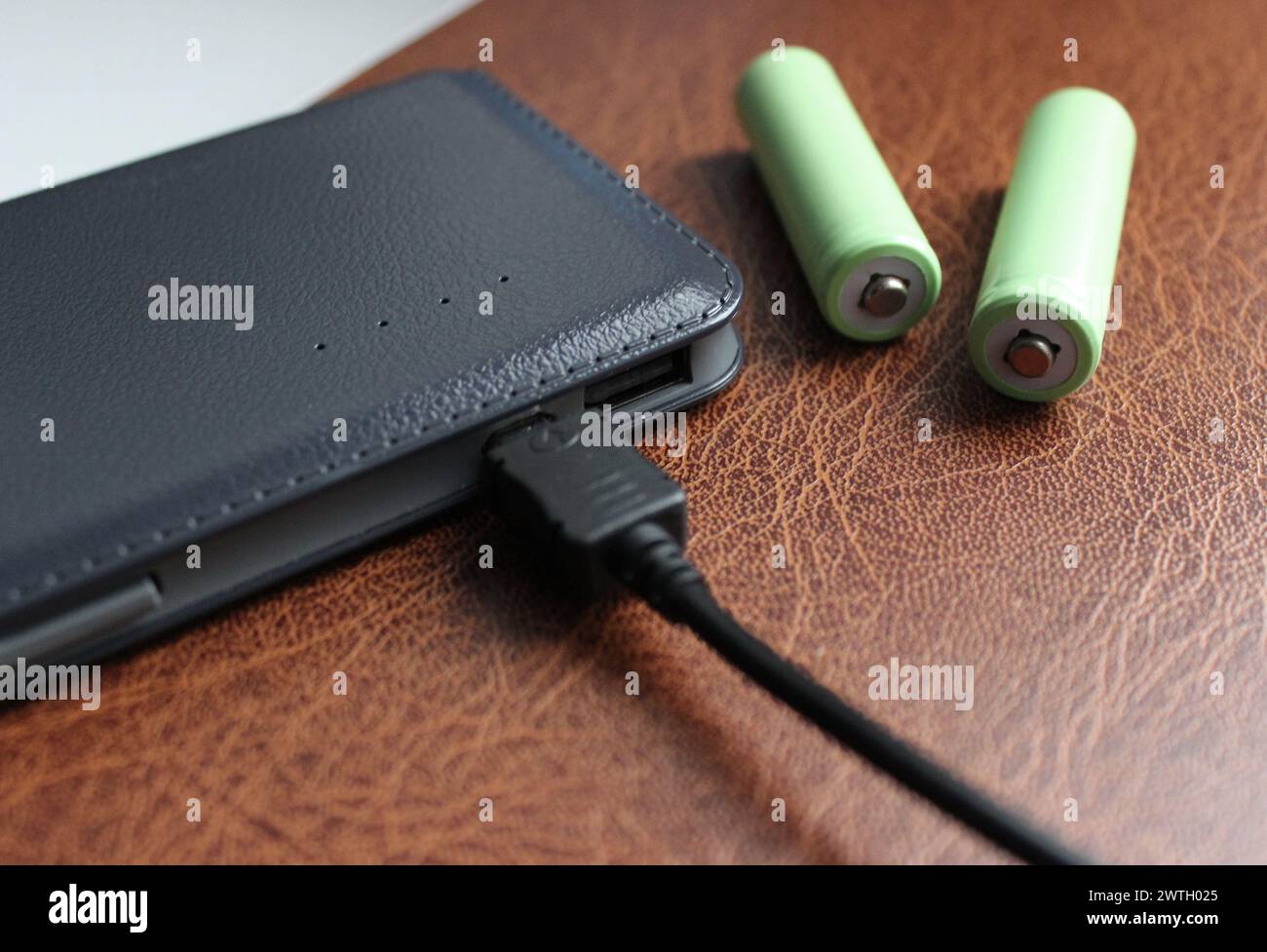 Tragbare Energiequellen. Wiederaufladbare AA-Batterien in der Nähe teurer Power Bank auf Einem Lederordner Stockfoto