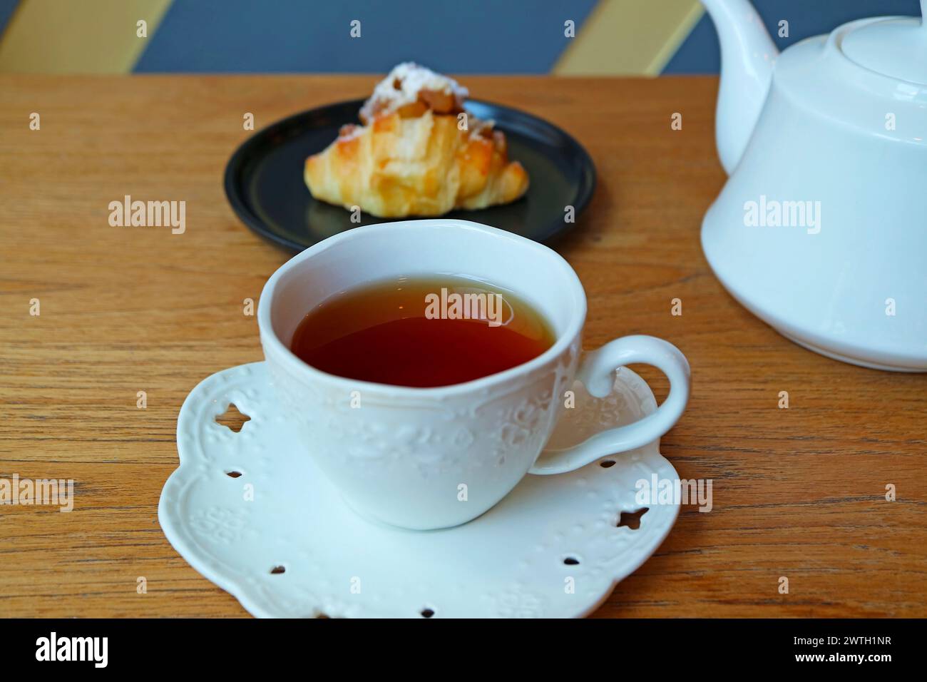 Tasse heißer Tee mit einem Teller Mandelcroissant im Hintergrund Stockfoto