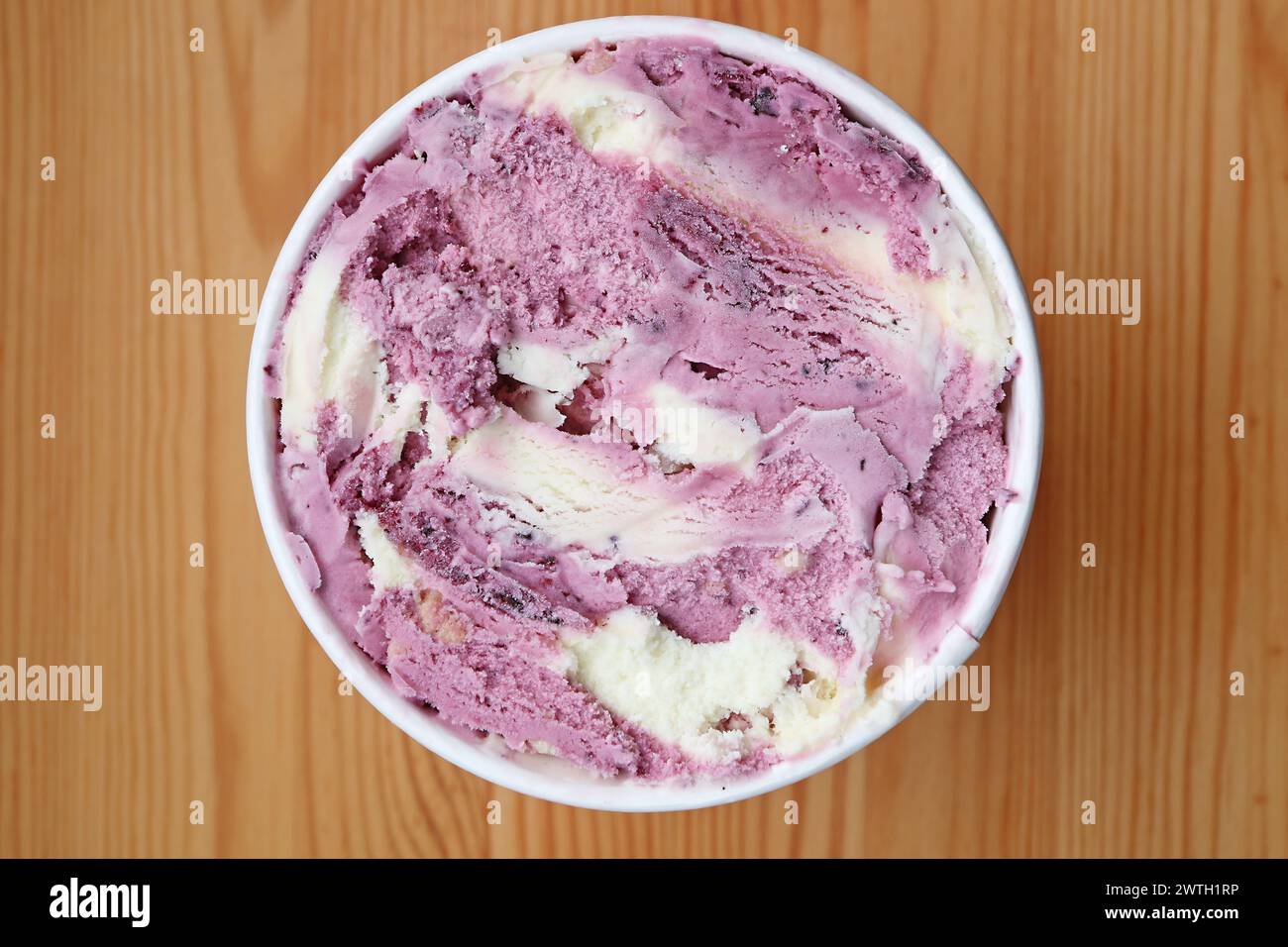 Blick von oben auf Blaubeeren-Joghurt-Eis in einer großen Tasse auf Holztisch Stockfoto