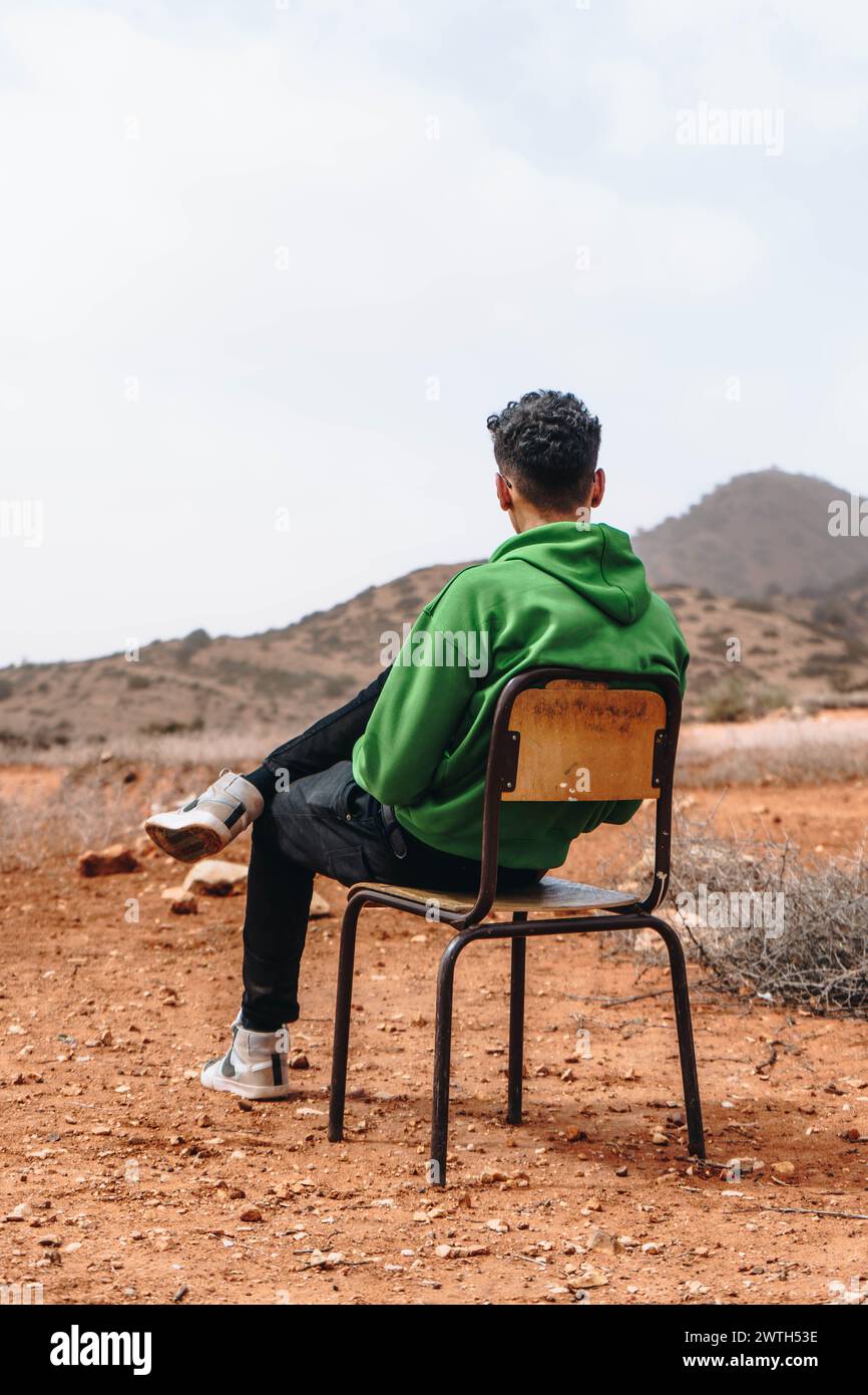 Ein junger Mann sitzt auf einem Stuhl auf einem Berg in Marokko. Stockfoto