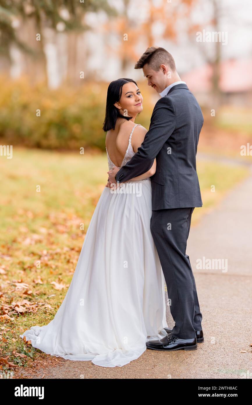 Die Braut blickt mit dem Bräutigam über die Schulter in die Kamera Stockfoto