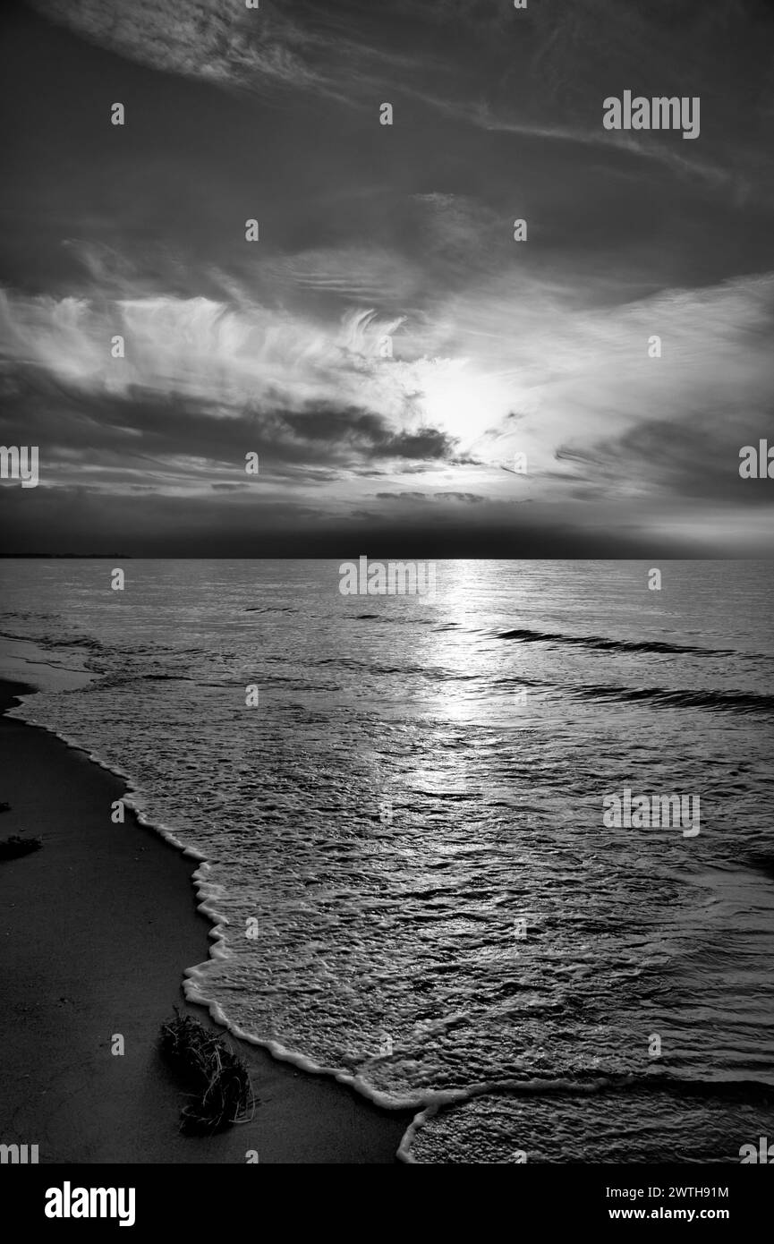 Sonnenuntergang am Meer in schwarz-weiß träumend. Sandstrand im Vordergrund. Sanfte Wellen. Ostsee. Landschaft an der Küste Stockfoto