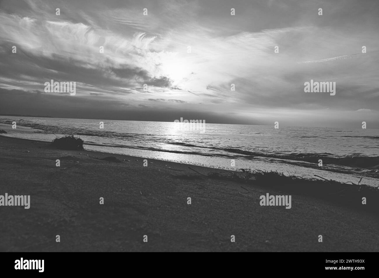 Sonnenuntergang am Meer in schwarz-weiß träumend. Sandstrand im Vordergrund. Sanfte Wellen. Ostsee. Landschaft an der Küste Stockfoto