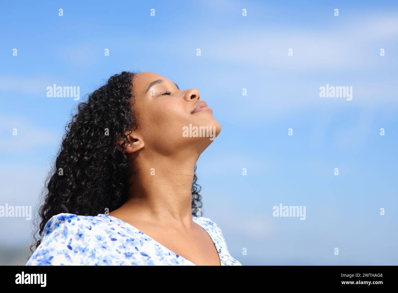 Schwarze Frau atmet frische Luft mit blauem Himmel im Hintergrund Stockfoto